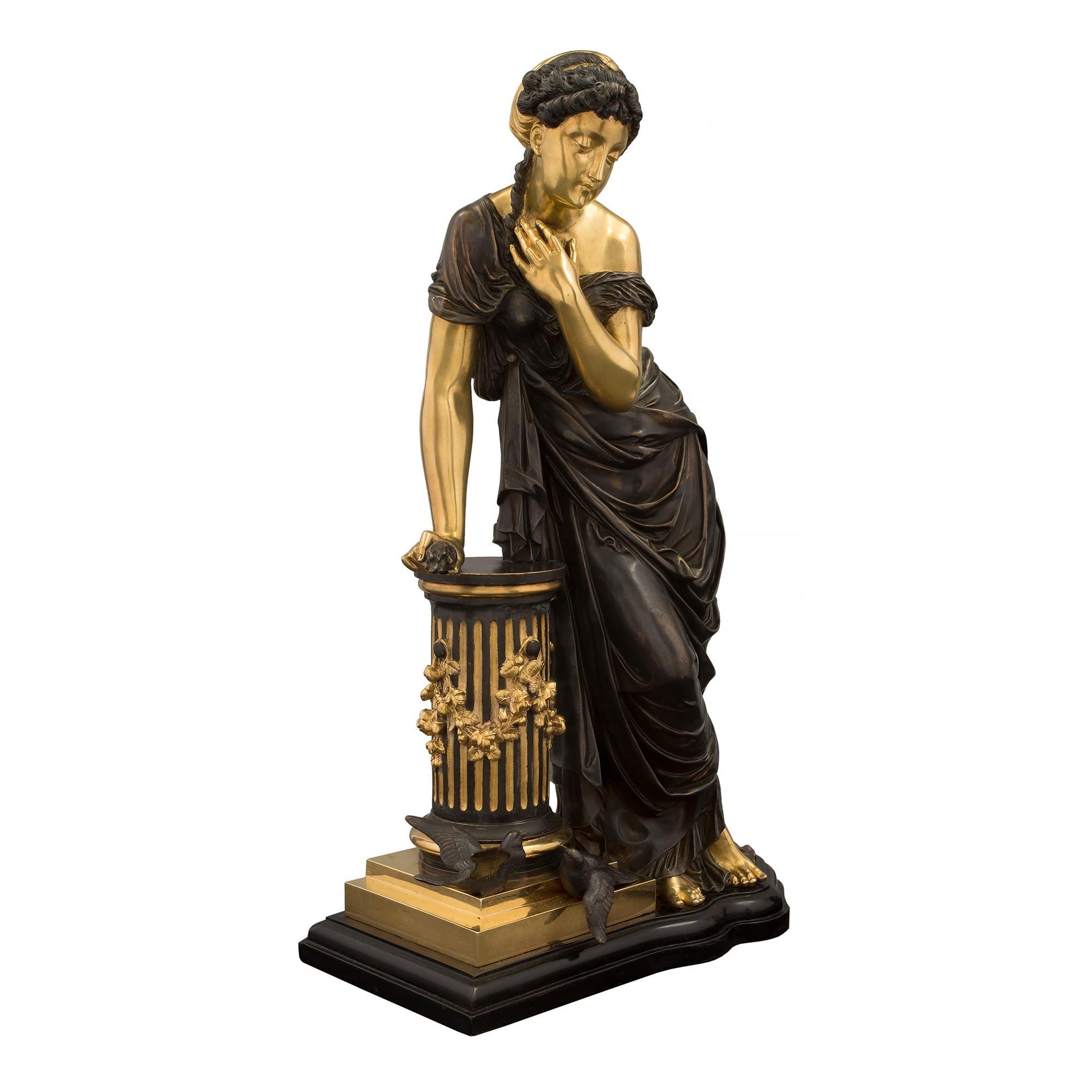 Très élégante statue d'une belle jeune fille en bronze patiné et bronze doré du XIXe siècle, attribuée à Pierre Louis Detrier. La statue est surélevée par une belle base de forme festonnée avec une bordure mouchetée où se tient la belle dame. La