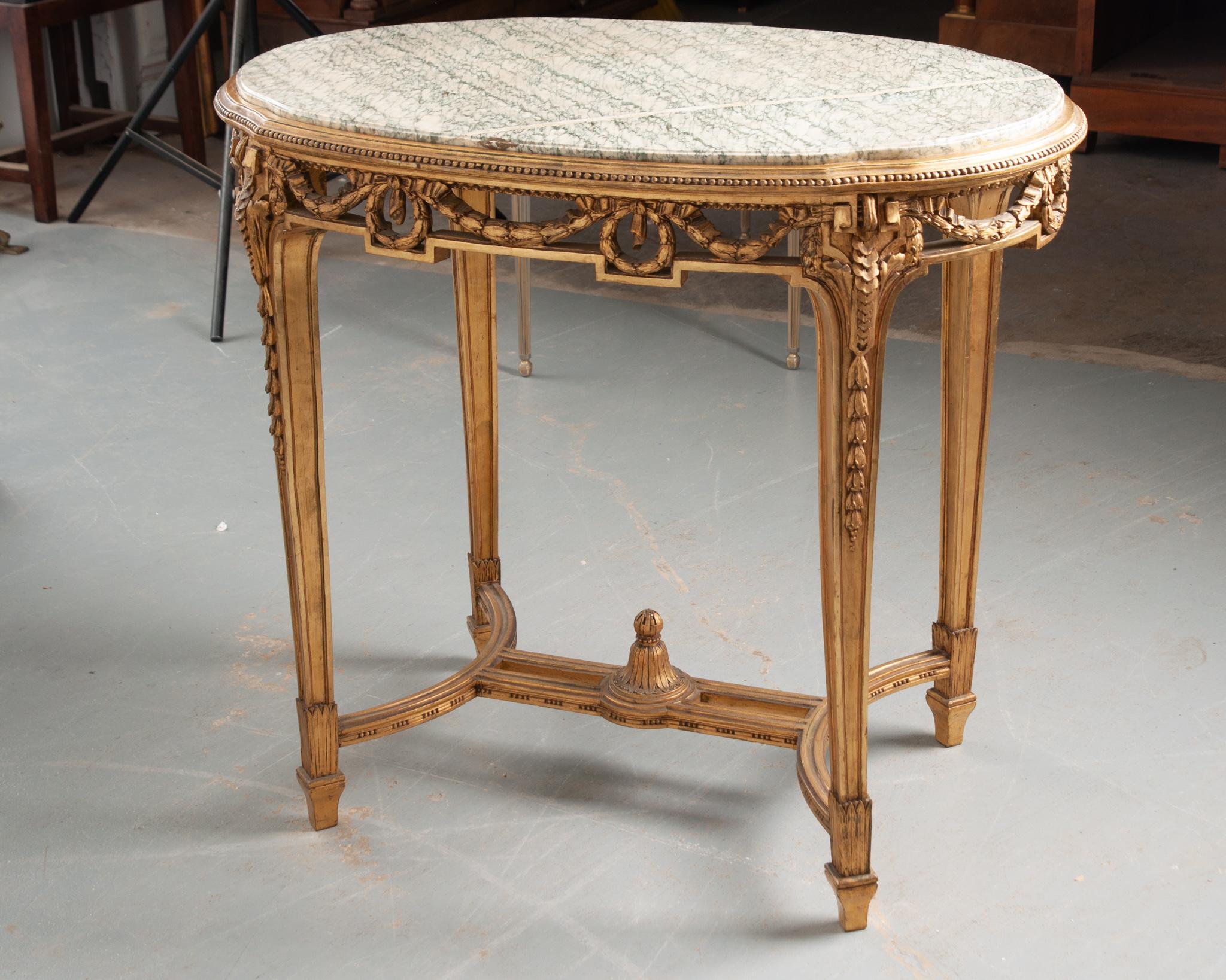A stunning Louis XVI style center table from 19th century France. The inset white marble top with striking green veining is in good antique condition. The gold gilt frame is incredibly carved; a bead perimeter borders the marble top and pierced