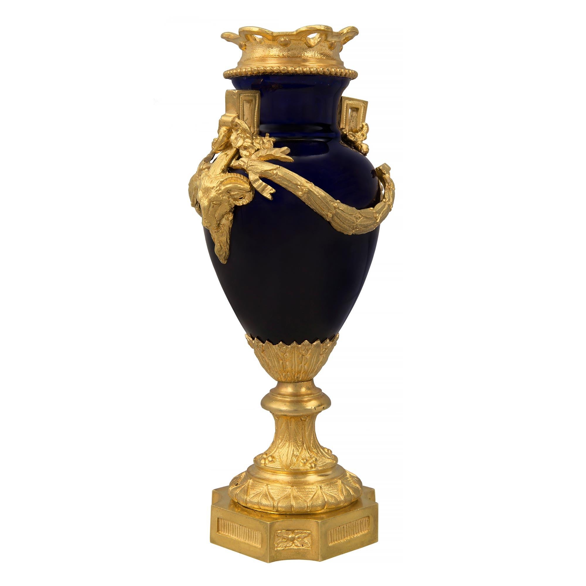 Remarquable vase de grande qualité en porcelaine bleu cobalt et bronze doré de style Louis XVI du 19e siècle, probablement de Sèvres. Le vase est surélevé par une fine base carrée en bronze doré avec des coins concaves, de belles plaques cannelées