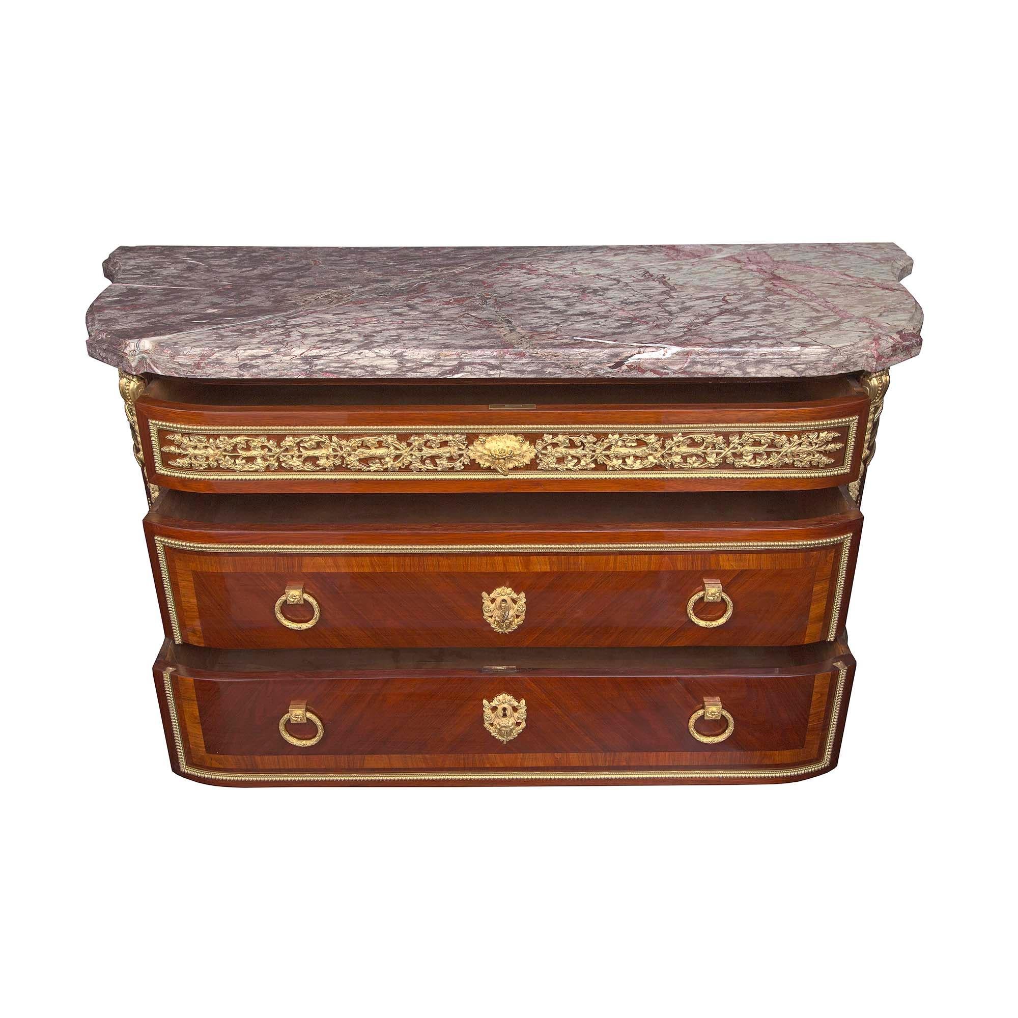 A striking and important French 19th century Louis XVI st. tulipwood, kingwood, and ormolu mounted 'D' shaped commode, attributed to Paul Sormani. The commode is raised by elongated inlaid topie shaped legs decorated by ormolu sabots with acanthus