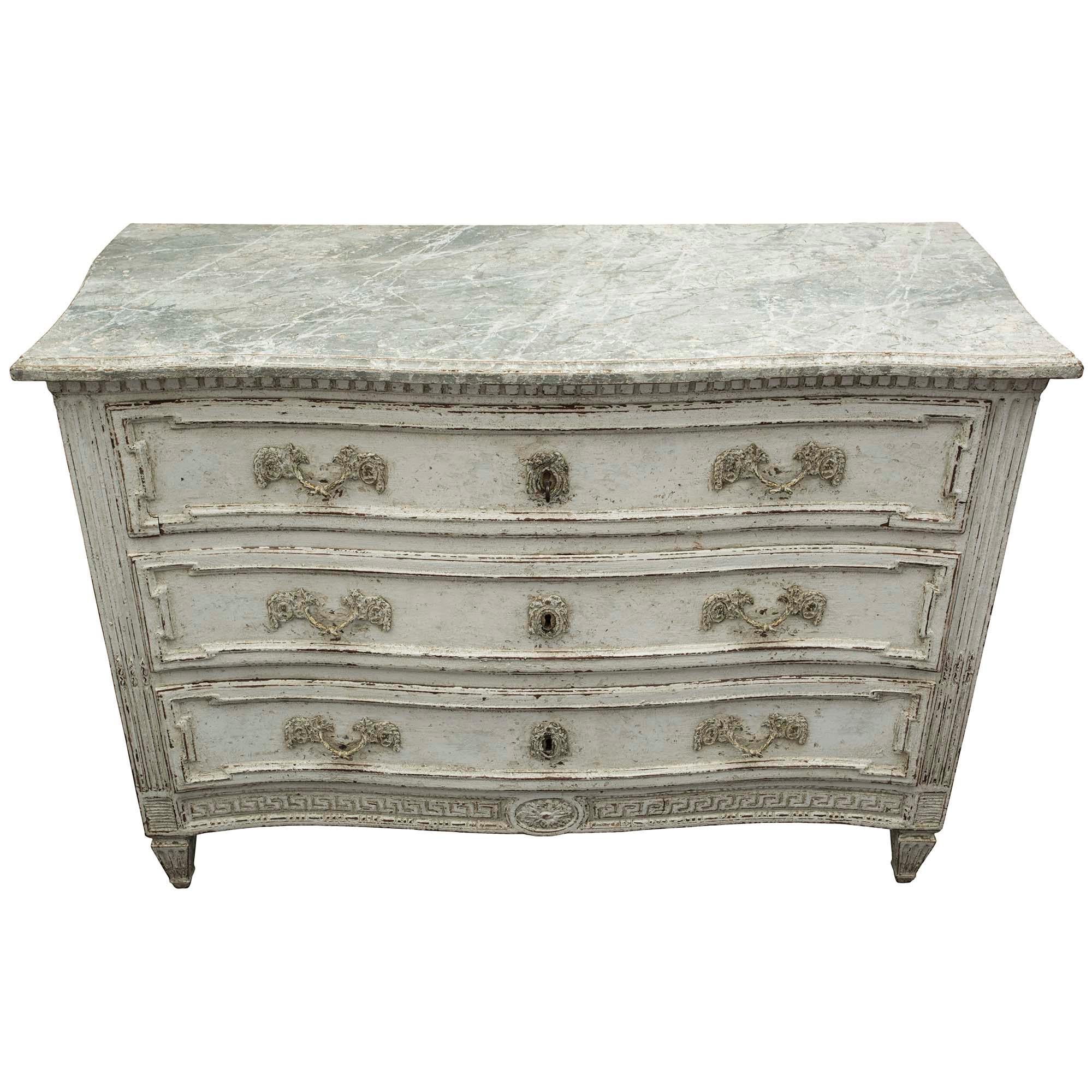 A most elegant country French 19th century Louis XVI style three-drawer commode with a wonderful patinated finish and faux marble top. The commode is raised by square tapered legs below vertical fluted columns with carved chandelles. The bottom