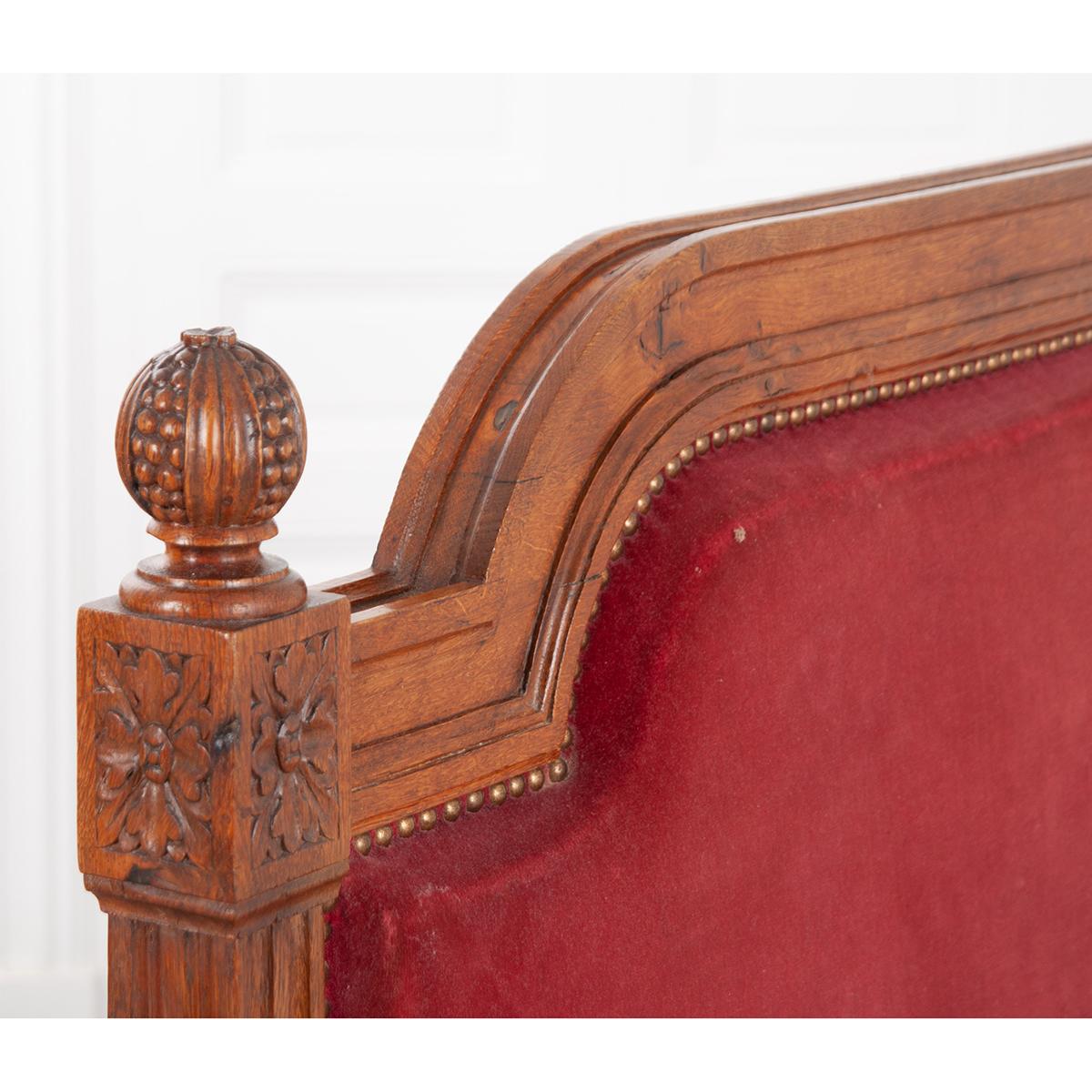 A French 19th century Louis XVI style carved oak daybed. The oak has a wonderful tone and patina. The headboard and the footboard are the same height with an arched top. It has square fluted columns on each side that frame the worn rose colored