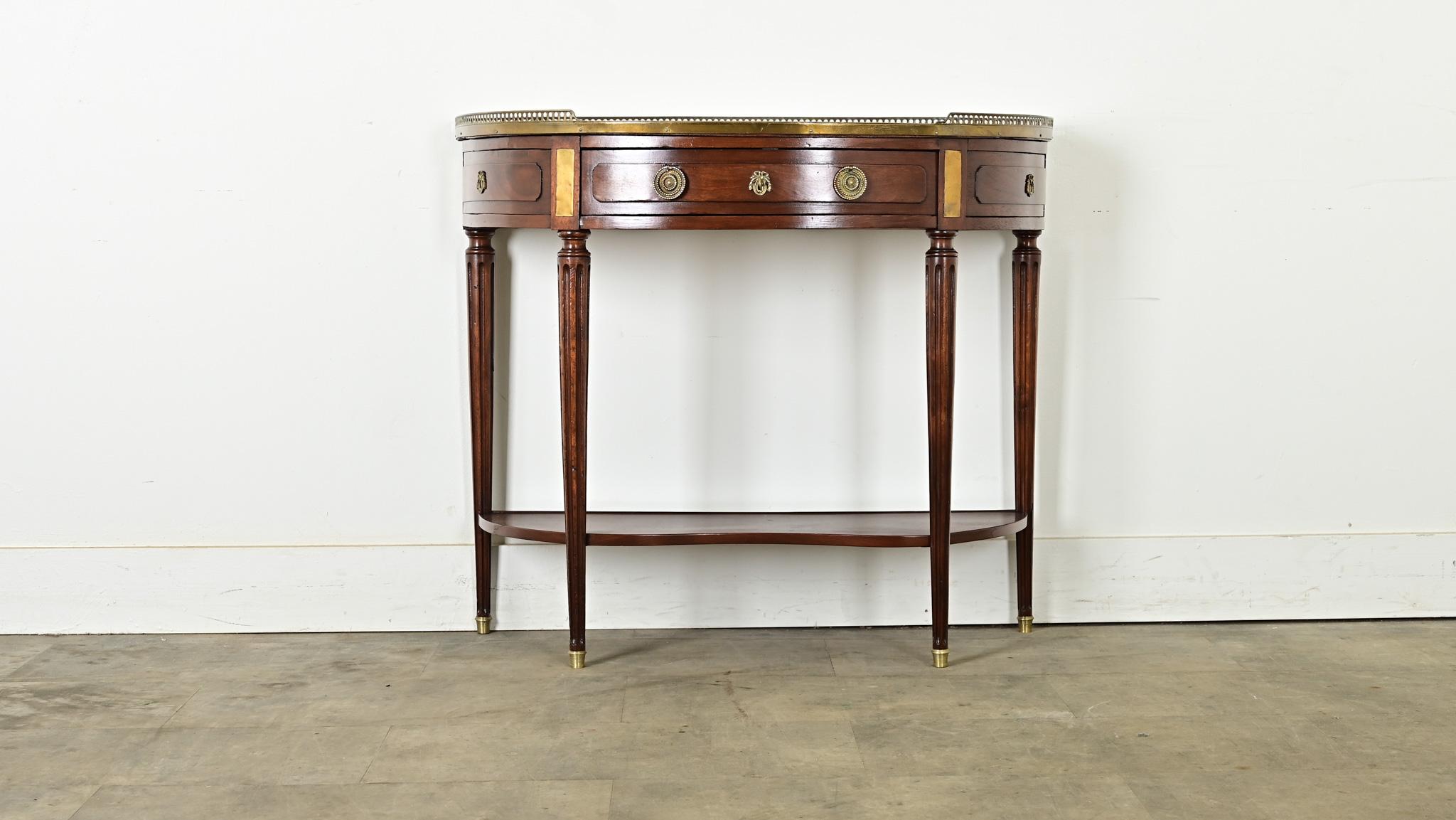 This elegant mahogany and marble demilune console from France, 19th century, is a fantastic addition to any space, as a console or even a small desserte table and bar. It is topped with an inset piece of white marble, surrounded by a pierced brass