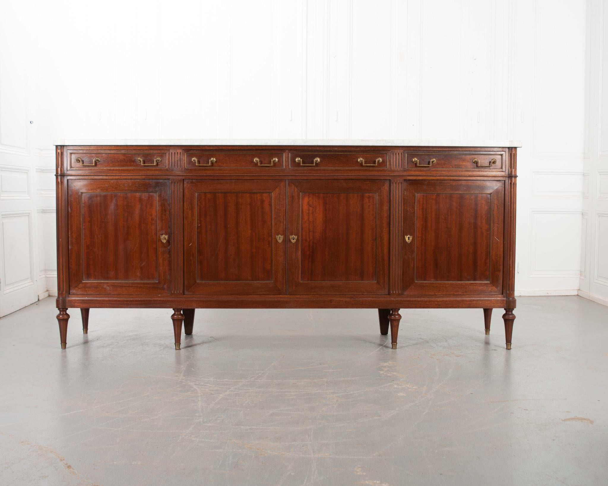French Louis XVI style mahogany enfilade with original white marble is circa 1880. Shaped to fit the enfilade, the marble top has an ogee edge and turret corners. The apron houses four drawers, all featuring a pair of rectangular brass pulls, andare