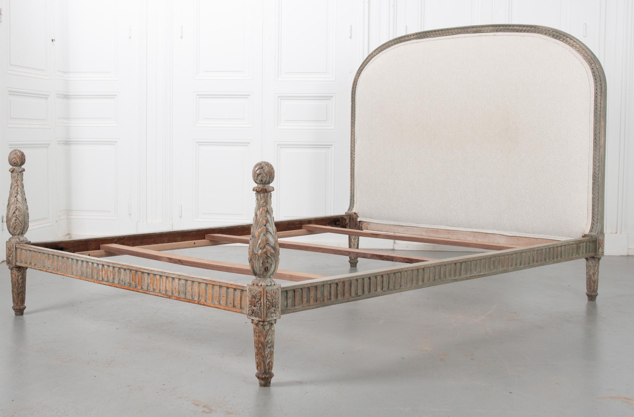 Beautifully carved details cover nearly 100% of this exceptional 19th century French Louis XVI-style bed’s frame. The wooden frame is comprised of an arched, upholstered headboard, its carved side rails, and two turned baluster posts that act as a
