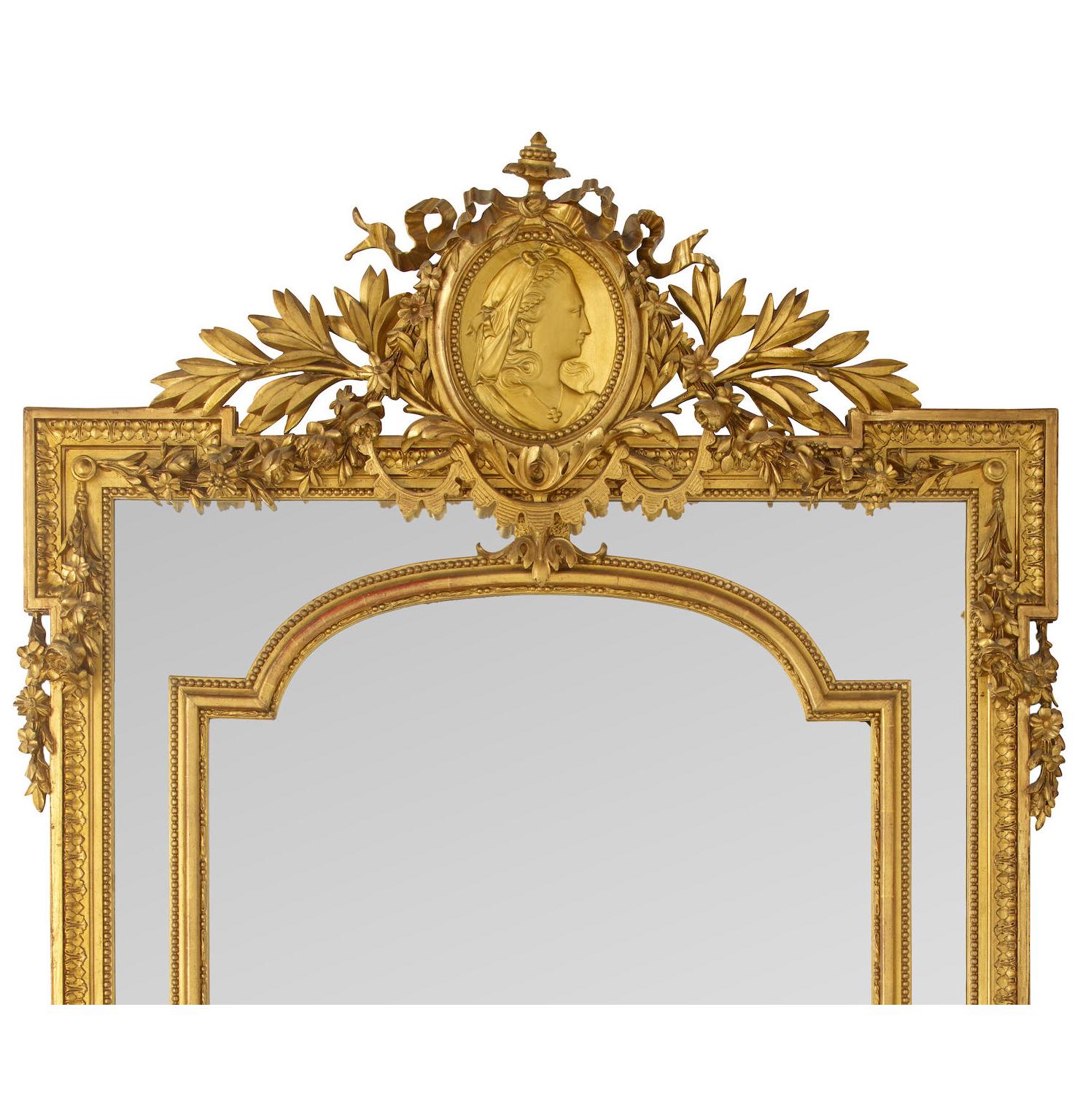 A Very Fine French 19th Century Louis XVI Style Gilt-Wood and Gilt-Gesso Carved Ornamental Mantel Pier Mirror. The ornately decorated giltwood carved frame crowned with a shield medallion of a maiden flanked by leaves, flower wreaths, ribbons and