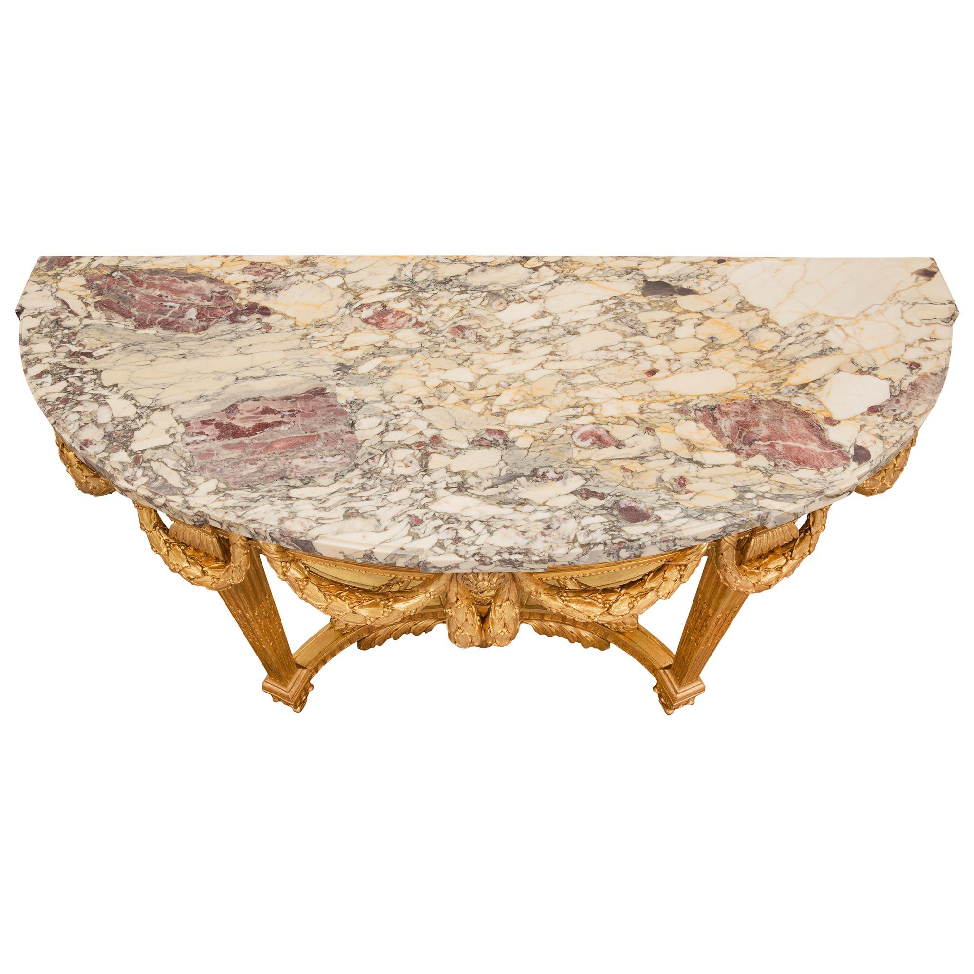 A most elegant and handsome French 19th century Louis XVI st. giltwood and Fleur de Pêcher marble console. The freestanding console is raised by fine square tapered fluted legs with beautiful foliate feet. Each leg is connected by a striking