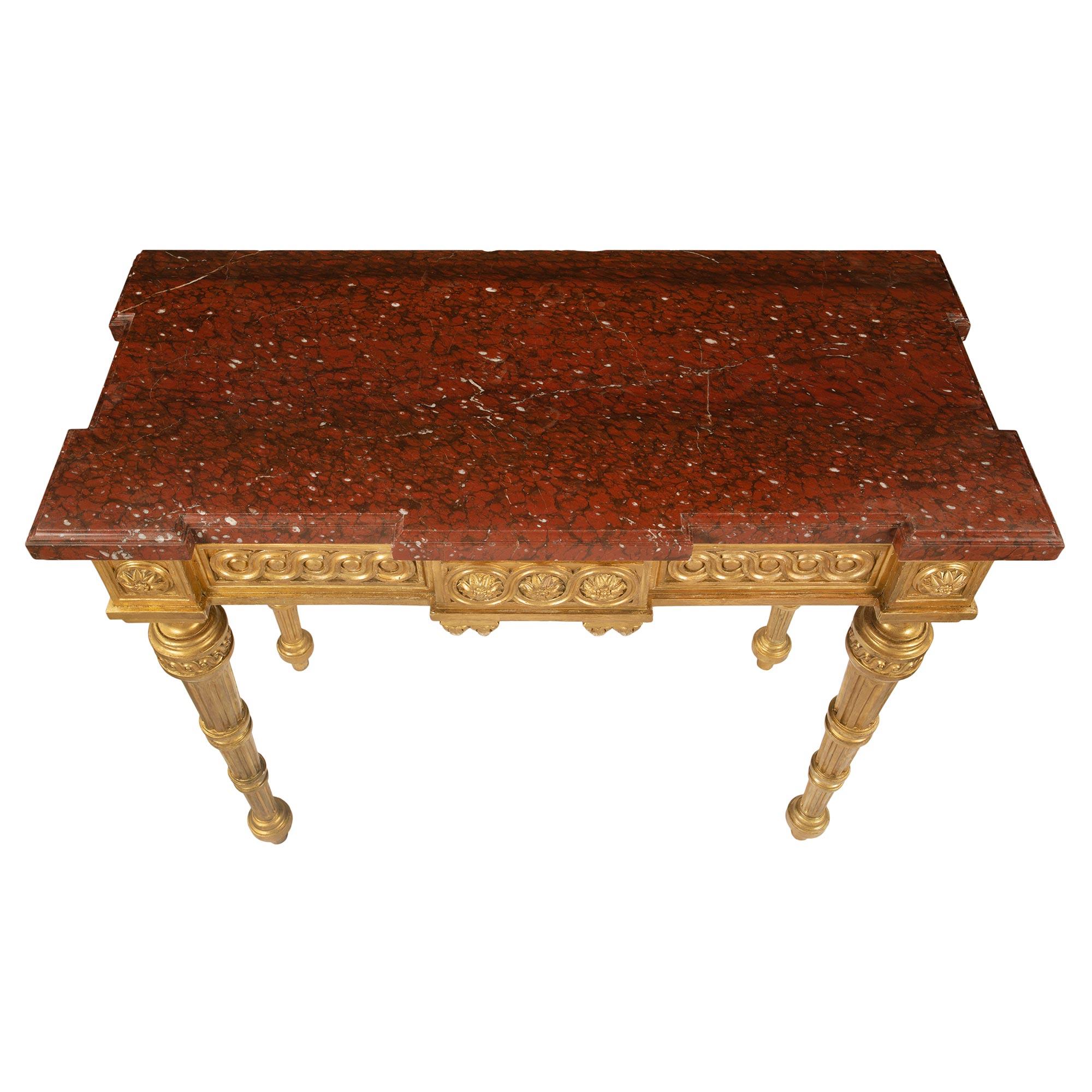 An extremely elegant French 19th century Louis XVI st. giltwood and Rouge Griotte marble freestanding console. The console is raised by circular tapered fluted legs with carved mottled designs, topie shaped feet and fine fitted Entrelacs et Les