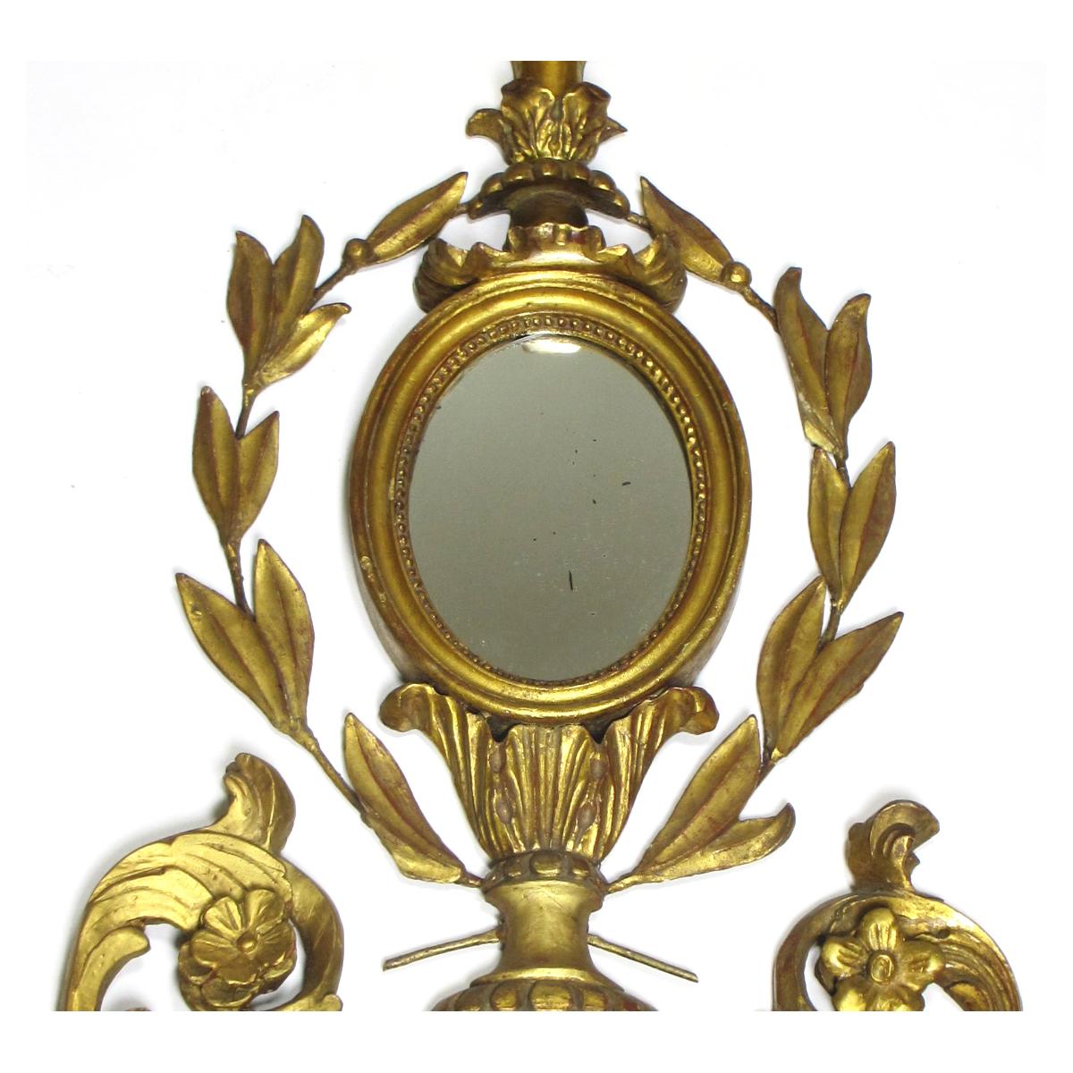 Un beau miroir d'applique (plafonnier) Girandle de style Louis XVI du 19e/20e siècle, en bois de tilleul sculpté. Le corps allongé sculpté est décoré de couronnes, de fleurs, de rayons de soleil et d'épis de faîtage sculptés en bois doré, au centre