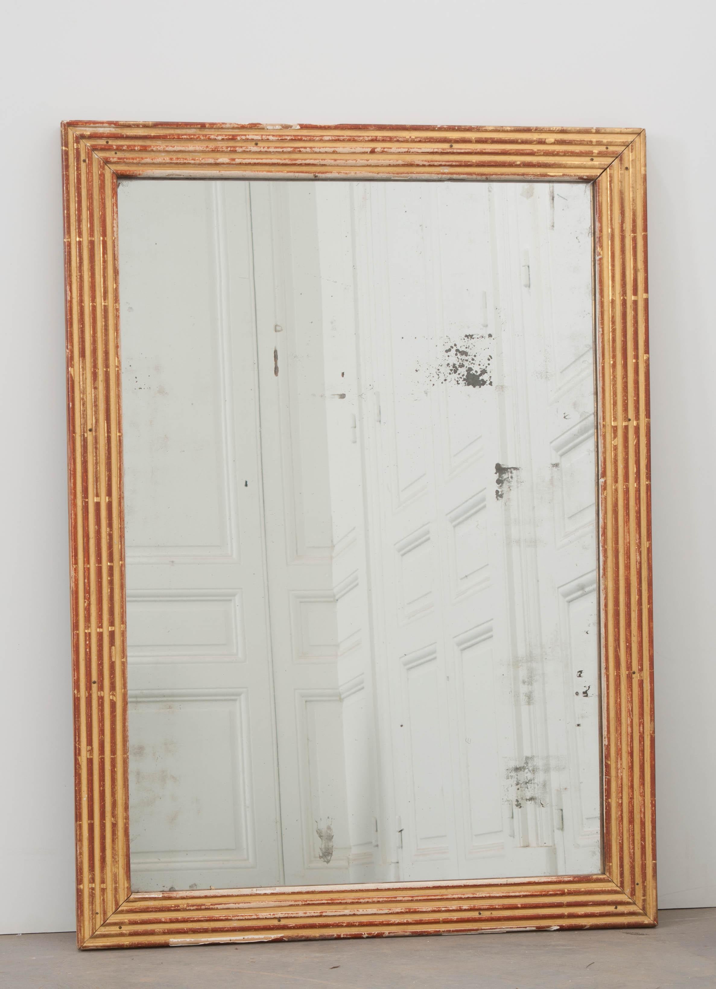 This handsome Louis XVI style reed-carved rectilinear giltwood mirror, circa 1870, was sourced in France and displays the right amount of wear and a rich patina for the 