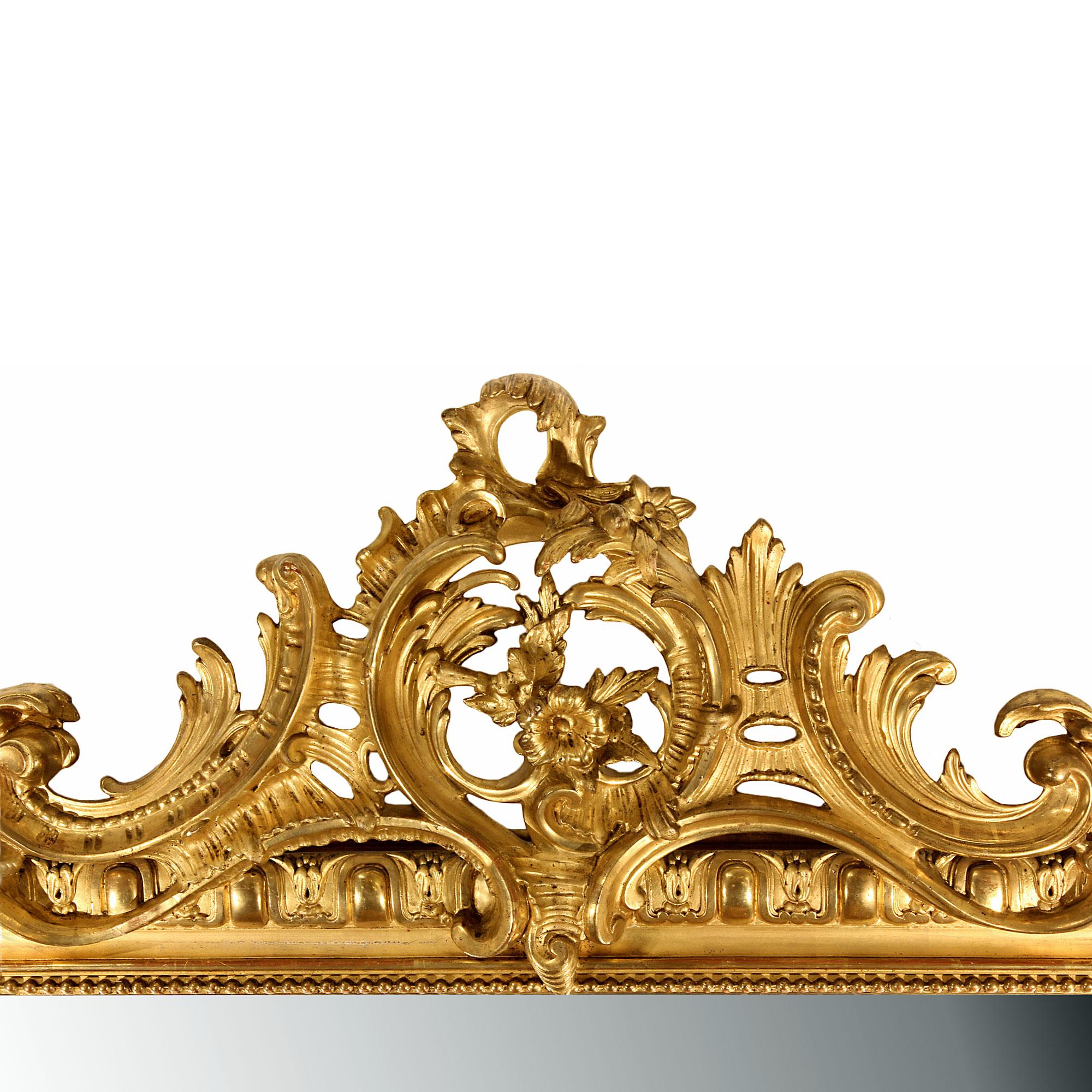 A very elegant mid 19th century French Louis XVI st. giltwood mirror. The richly decorated frame has a large S scrolled acanthus leaf with flowers at the bottom. The vertical sides have an outer egg and dart design and an inner beaded trim. The top