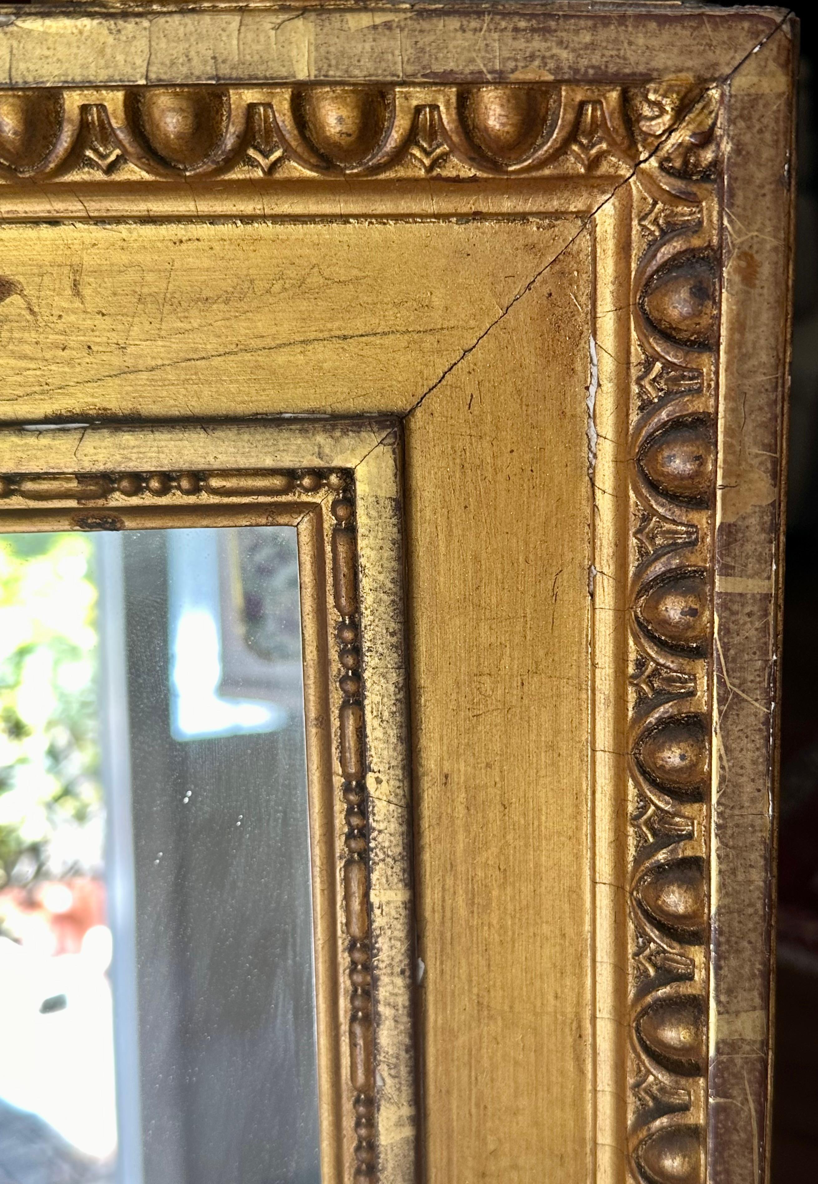 French 19th Century Louis XVI Style Large Gilded Wall Mirror

Large 19th century French Louis XVI style gilded wall mirror. Beautiful and elegantly designed frame with egg and dart edging. The crest features wreath and ribbon. Two urns adorned the