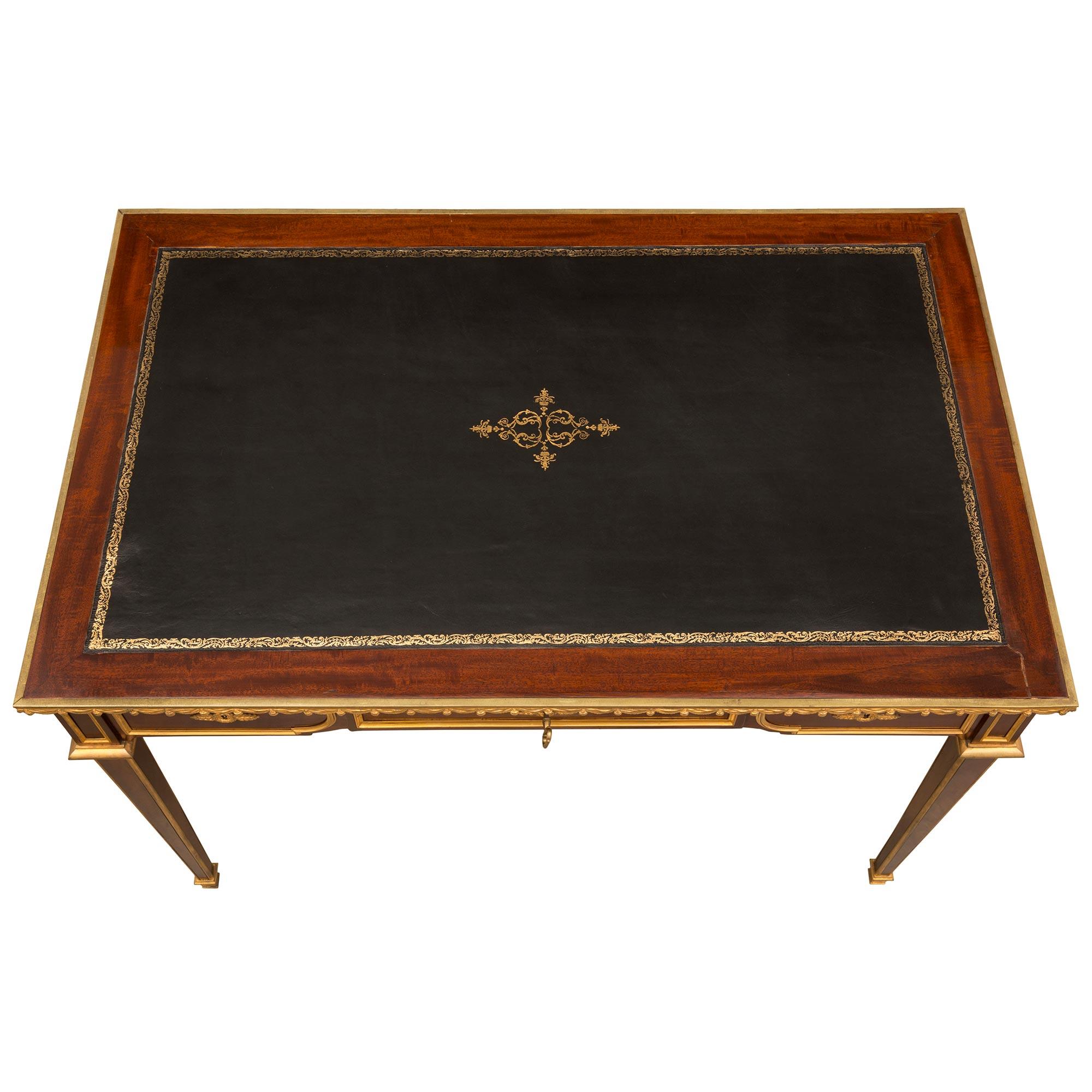 A superb French 19th century Louis XVI style mahogany and ormolu desk. The desk is raised by slender tapered legs with ormolu trim finished with ormolu sabots and top crown. The impressive apron has three drawers with ormolu keyhole escutcheons and