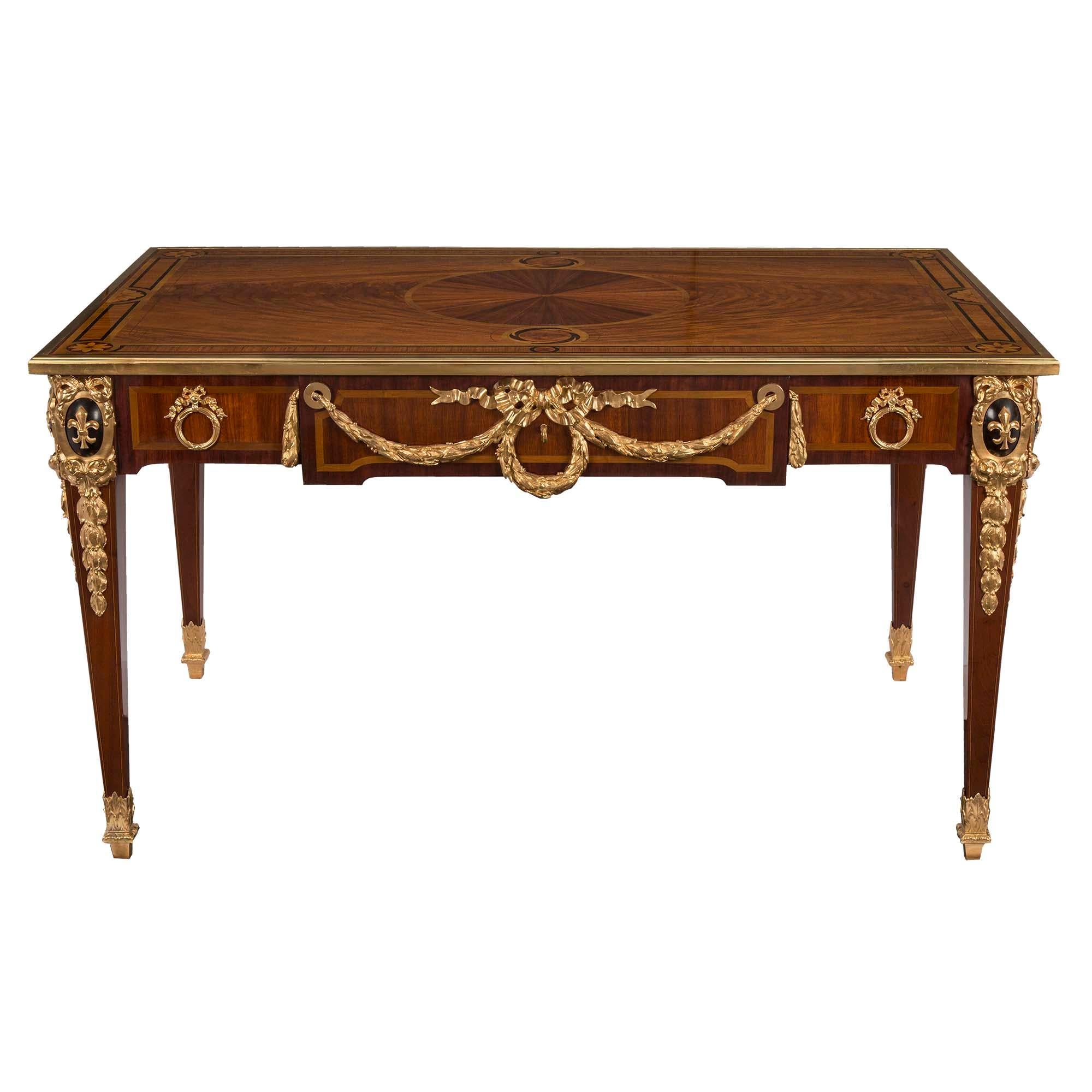 A very handsome and impressive French 19th century Louis XVI style mahogany and ormolu inlaid Bureau Plat. The desk is raised on tapered legs with square ormolu topie feet and ormolu acanthus leaf sabots. The frieze has a kingwood inlay with