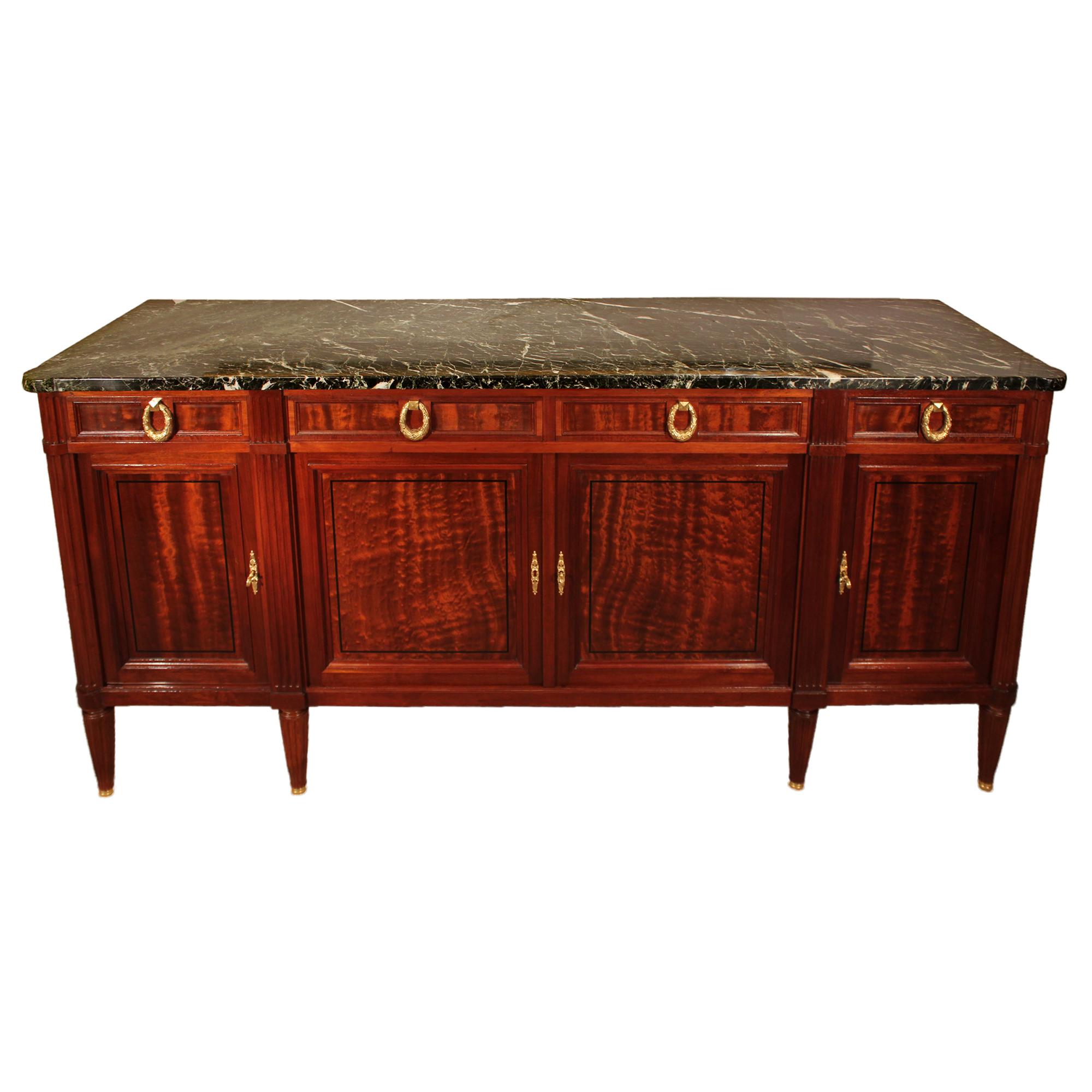 A fine quality French 19th century Louis XVI style mahogany and ebony buffet. The buffet is raised by circular fluted tapered legs ending with ormolu sabots. Above the straight frieze are four paneled doors with inlaid ebony trim and mottled border,