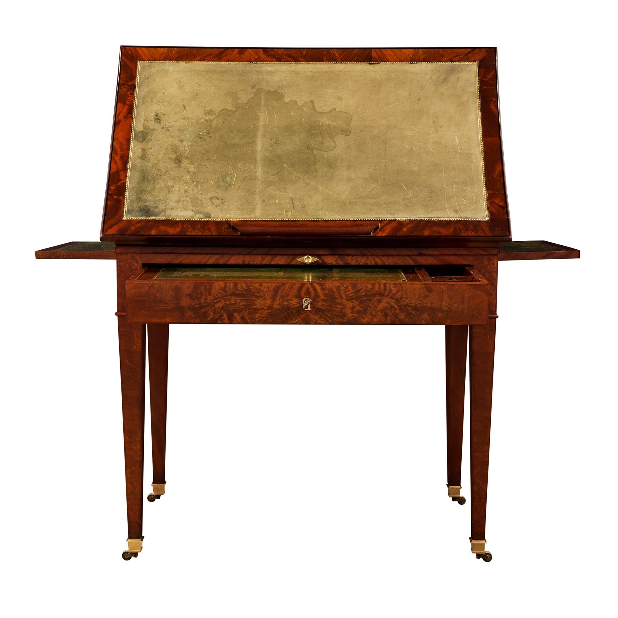 Ein attraktiver und ungewöhnlicher französischer Mahagonischreibtisch 'A la Tronchin' aus dem 19. Jahrhundert im Stil Louis XVI. Der Schreibtisch steht auf quadratischen, spitz zulaufenden Beinen mit originalen Ormolu-Sabots und -Rollen. Die gerade