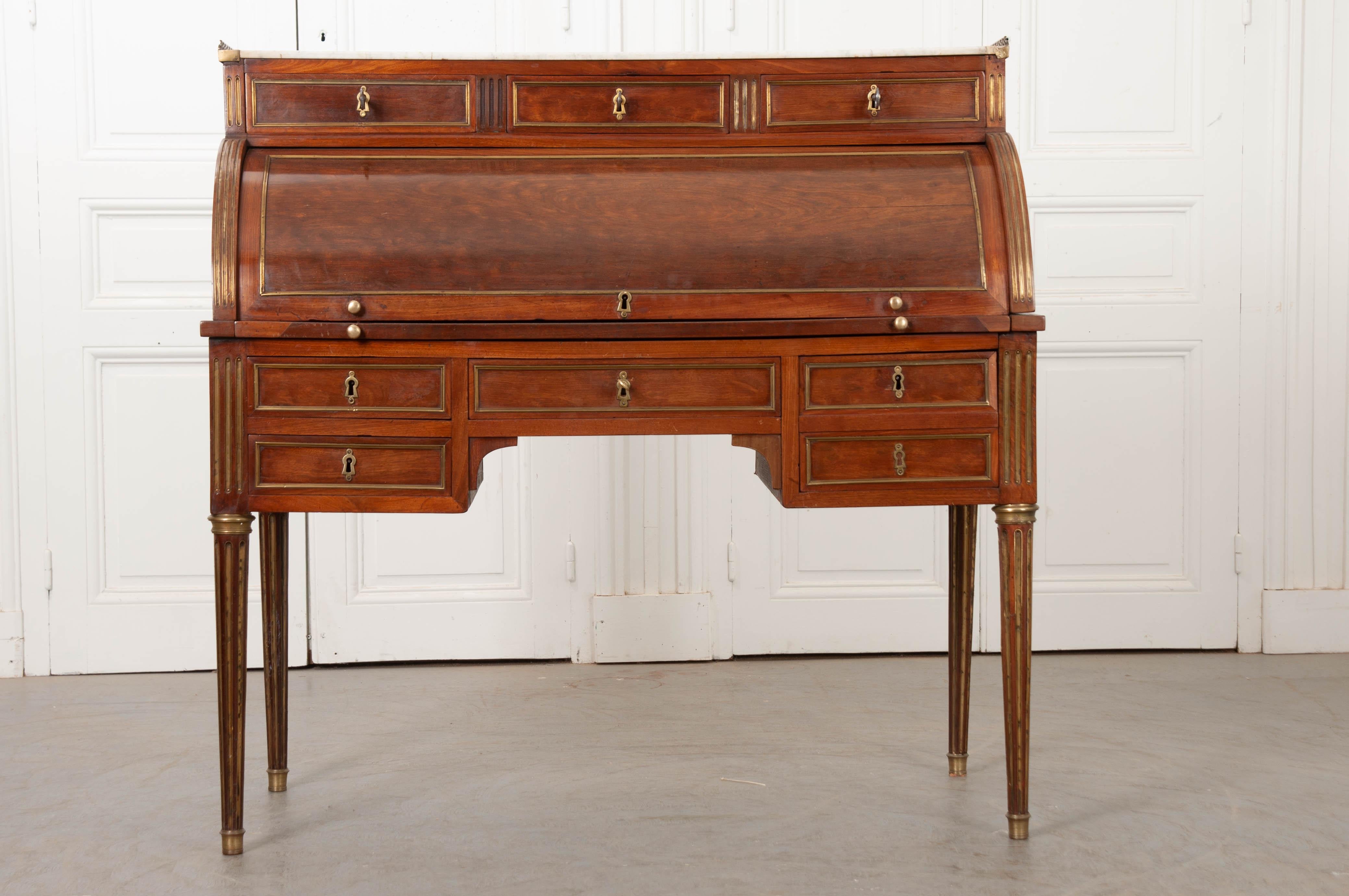 A gorgeous mahogany roll top desk, done in the Louis XVI style, from 19th century, France. The desk has a rectangular galleried marble top with cracks that have not been repaired.  See detailed photos for condition.  Directly under the marble top