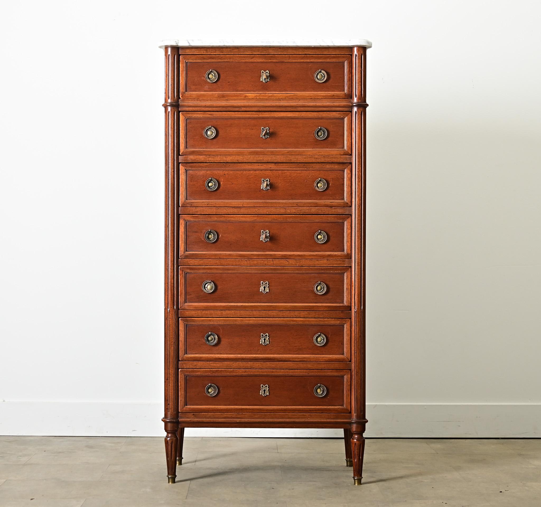 French mahogany 19th century semainier–made in the Louis XVI style–this Neoclassical dresser offers seven drawers (one for each day of the week) outlined in paneling and crowned with a marble top. The top surface of white marble has been finished