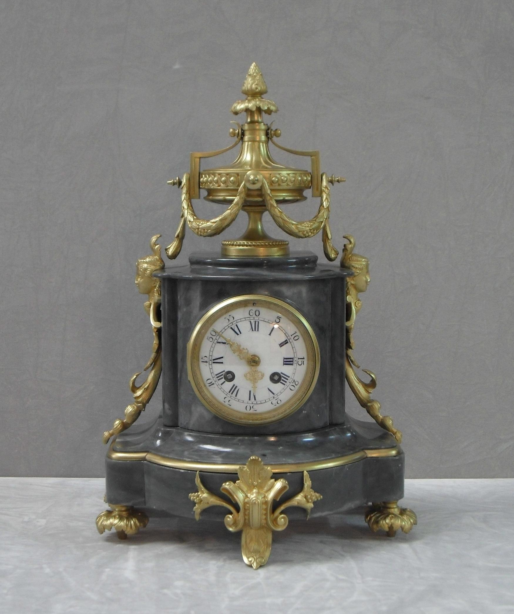 A very impressive French grey marble and bronze gilt ormolu clock set comprising of two four branch candelabra garnitures and a mantel clock in the Louis XVI style. The candelabras have a scrolling leaf and floral branch design with marble urn stood