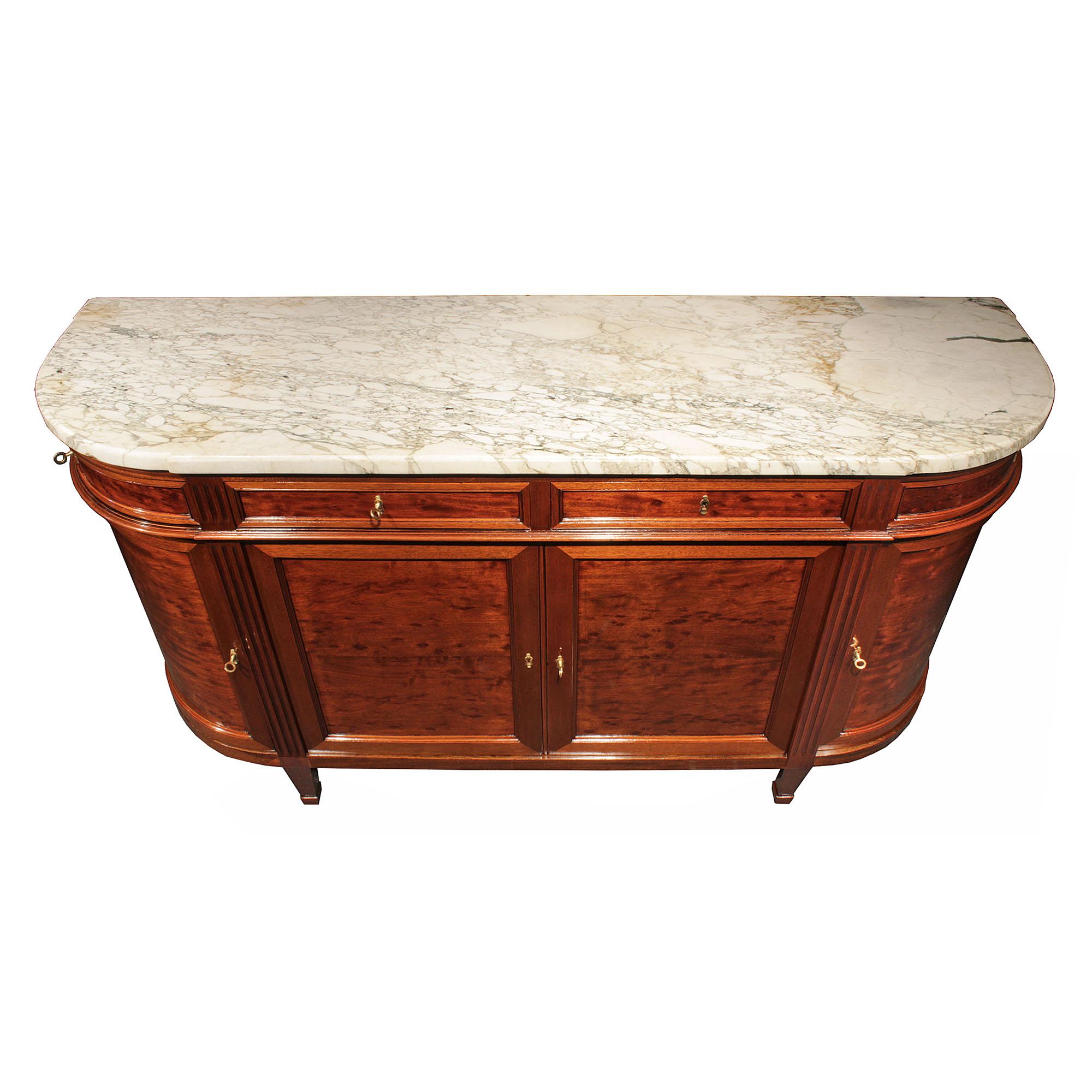 A handsome French 19th century Louis XVI st. mouchettte mahogany buffet. The rounded side buffet with four doors and four drawers is raised on tapered feet. The two central paneled doors with ormolu keyhole escucheons, are flanked with reeded