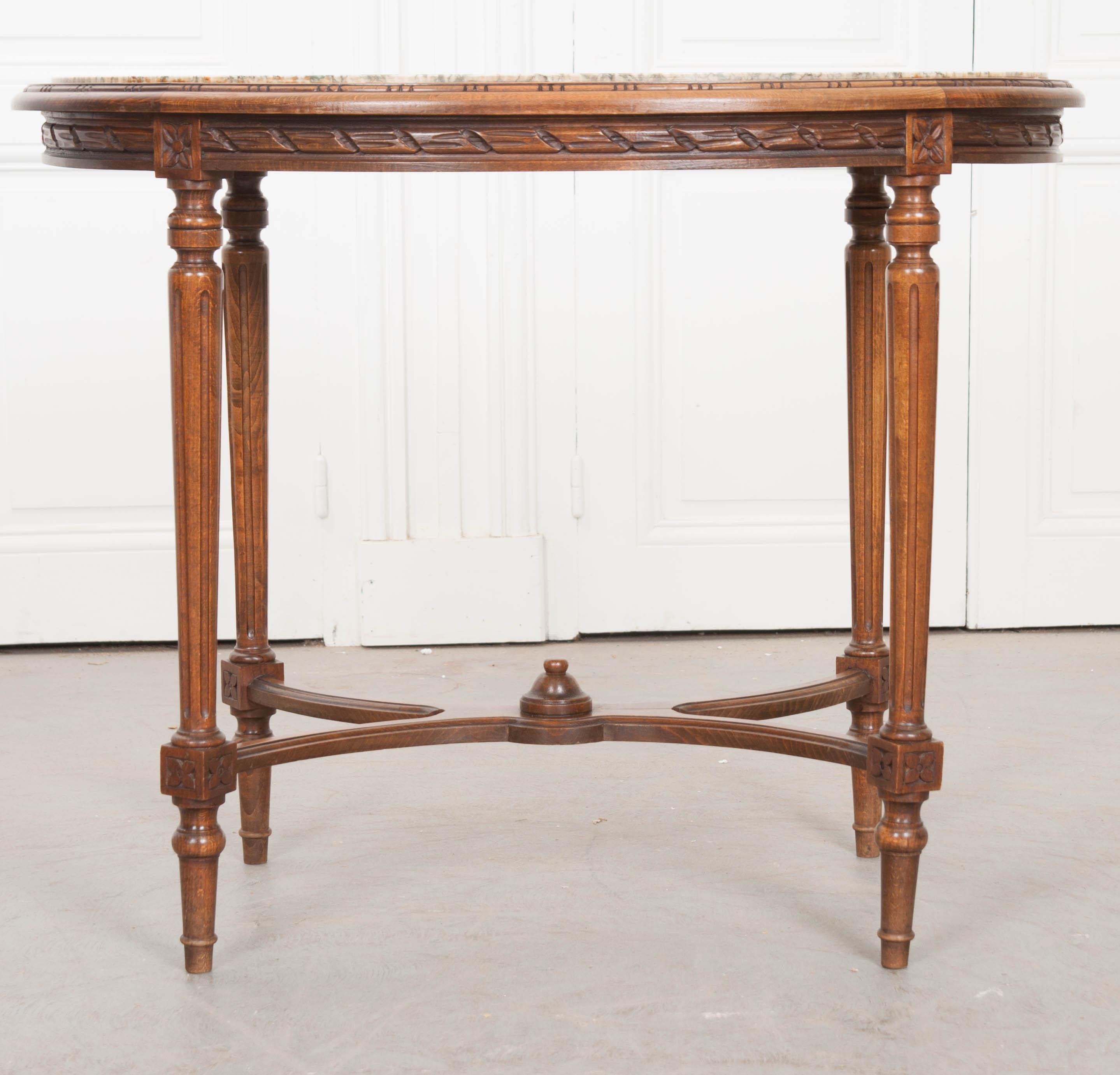 A spectacular French Louis XVI style oval marble-top table, made of hand carved oak from the 19th century. This beautiful antique features an oval shaped marble surface that is set into the top, and is in remarkable antique condition. The apron is