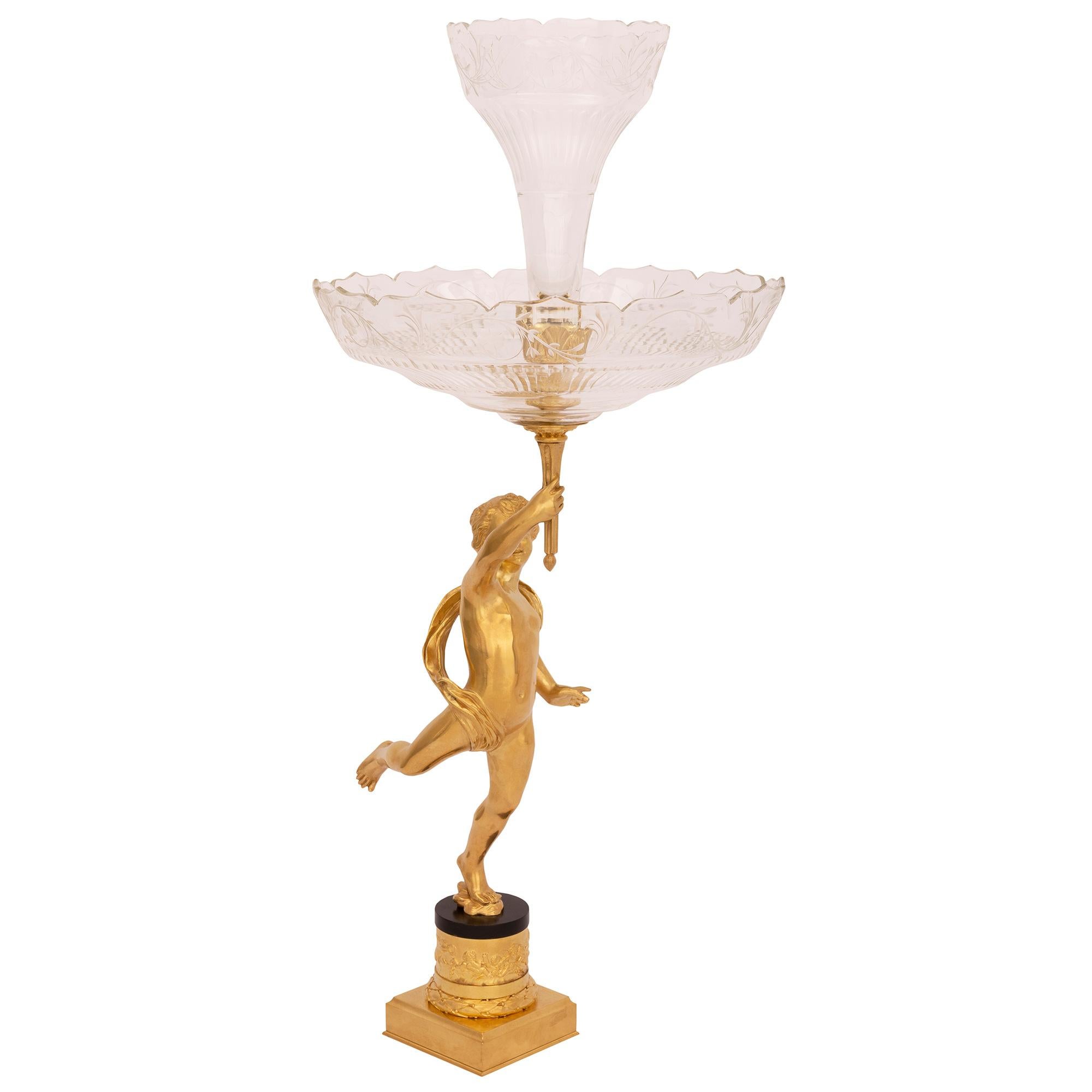 A most elegant French 19th century Louis XVI st. ormolu and crystal centerpiece. The centerpiece is raised by a fine square base with a richly chased wrap around berried laurel band and intricately detailed scenes of charming cherubs playing. At the
