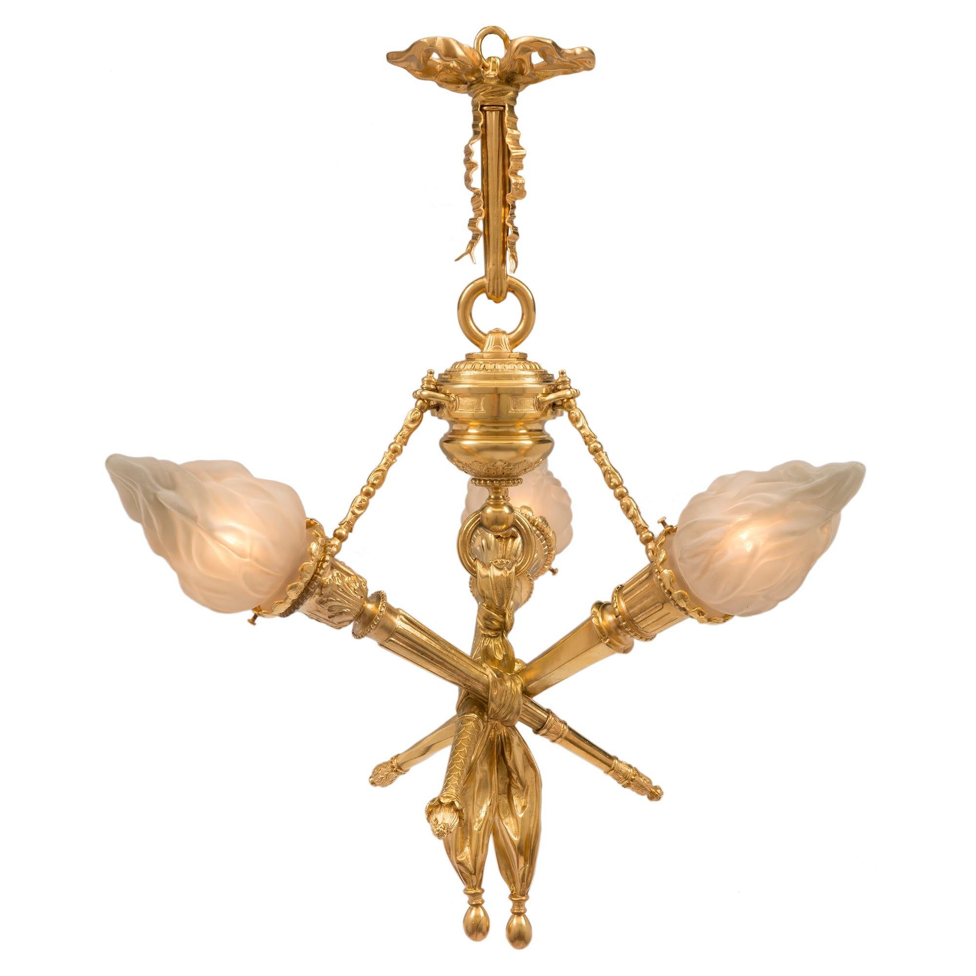 A striking and very unique French 19th century Louis XVI st. ormolu and frosted glass three light chandelier. At the center are three statement making ormolu torches which are bound together by a wonderfully executed tied flowing fabric. Each torch