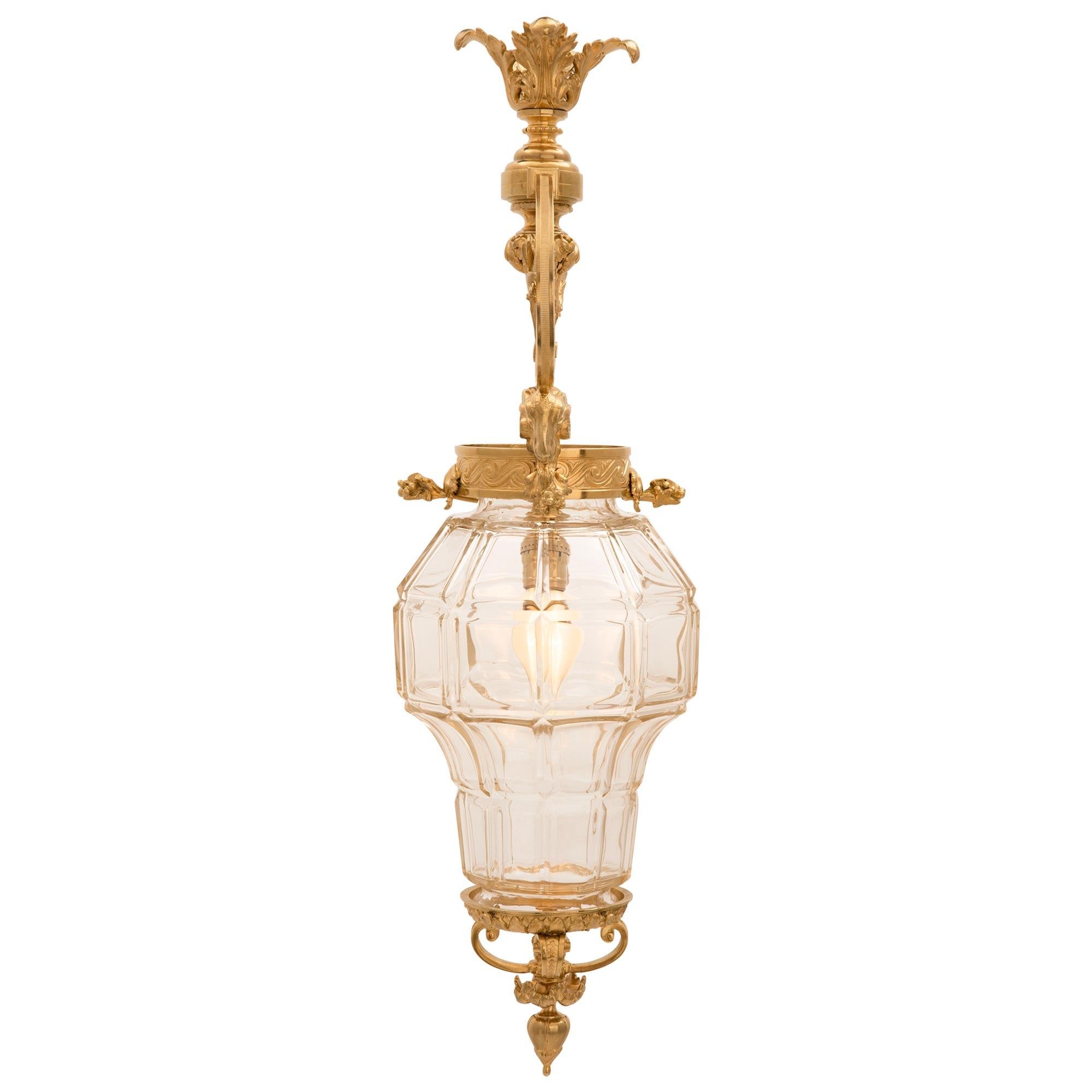 A charming French 19th century Louis XVI st. ormolu and glass lantern. The lantern is centered by an elegant bottom floral finial below lovely scrolled foliate designs. At the center is the beautiful cut glass body leading up to fine Vitruvian