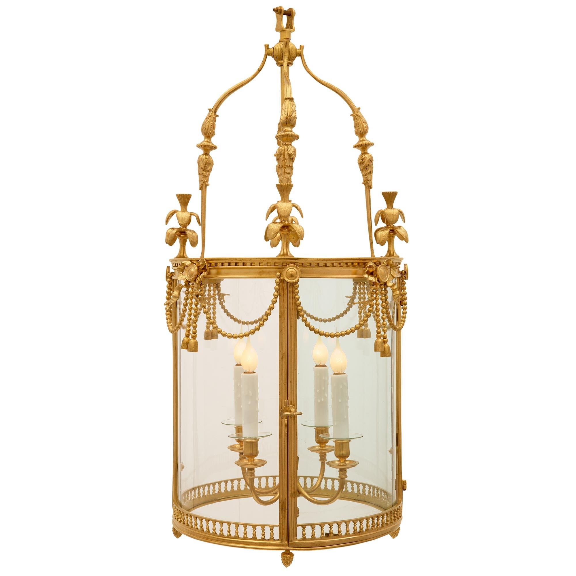 Une charmante et extrêmement décorative lanterne française du 19ème siècle de style Louis XVI en bronze doré et verre. La lanterne présente une fine bande percée en forme de balustre entourée de bronze doré à la base, avec quatre fines finales en