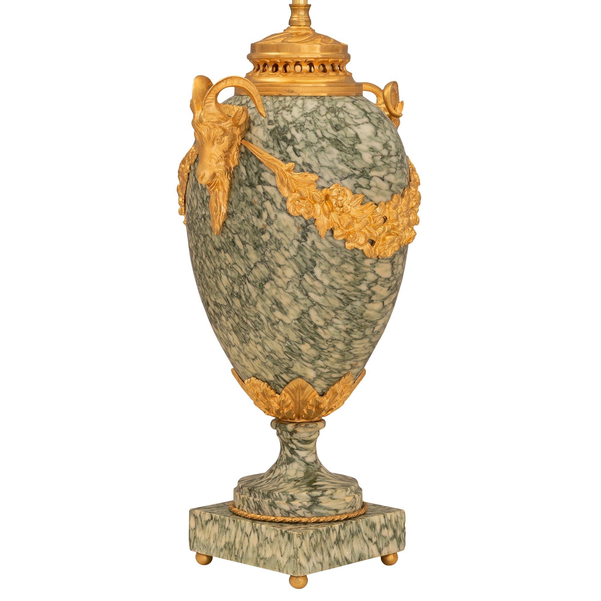 An elegant pair of French 19th century Louis XVI st. ormolu and marble urns mounted into lamps. Each lamp is raised by a square marble base below the richly chased satin and burnished finished socle pedestal with a twisted and fluted design is