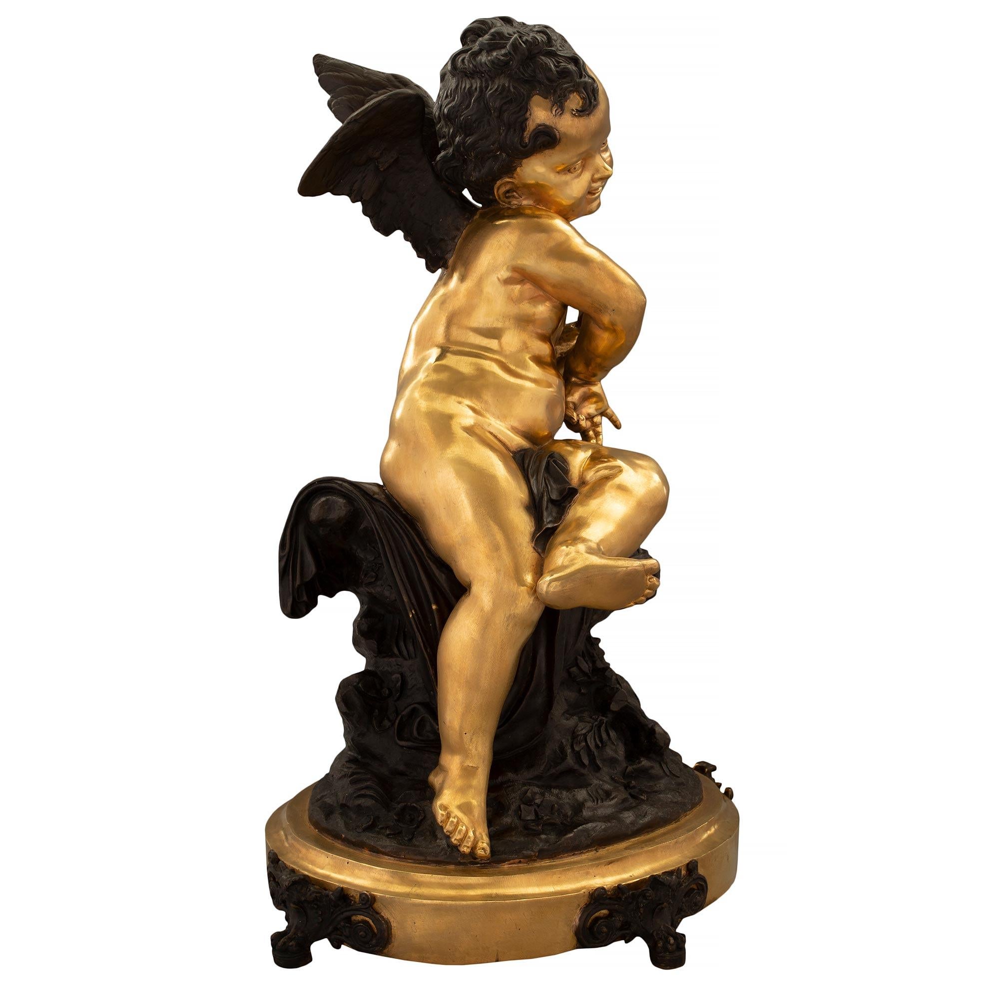 Charmante statue signée en bronze patiné et bronze doré de style Louis XVI du 19ème siècle. La statue est surélevée par une base ovale en bronze doré avec une bordure mouchetée et des pieds très décoratifs en bronze patiné percé à volutes.