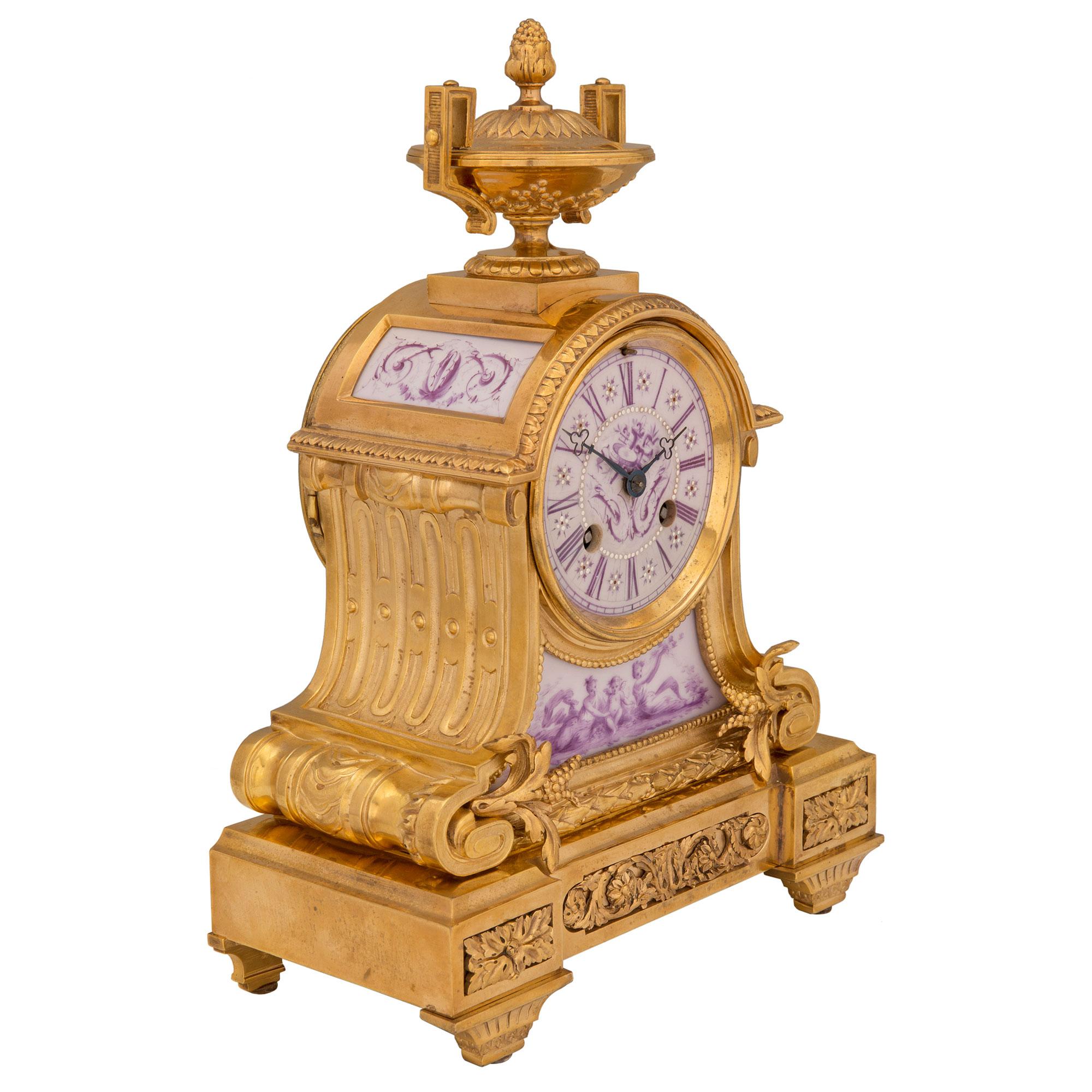 An elegant French 19th century Louis XVI St. ormolu and porcelain clock. The small scale clock is raised by fine tapered fluted legs below striking richly chased block rosettes centering a lovely pierced rinceau shaped fitted ormolu plaque. The