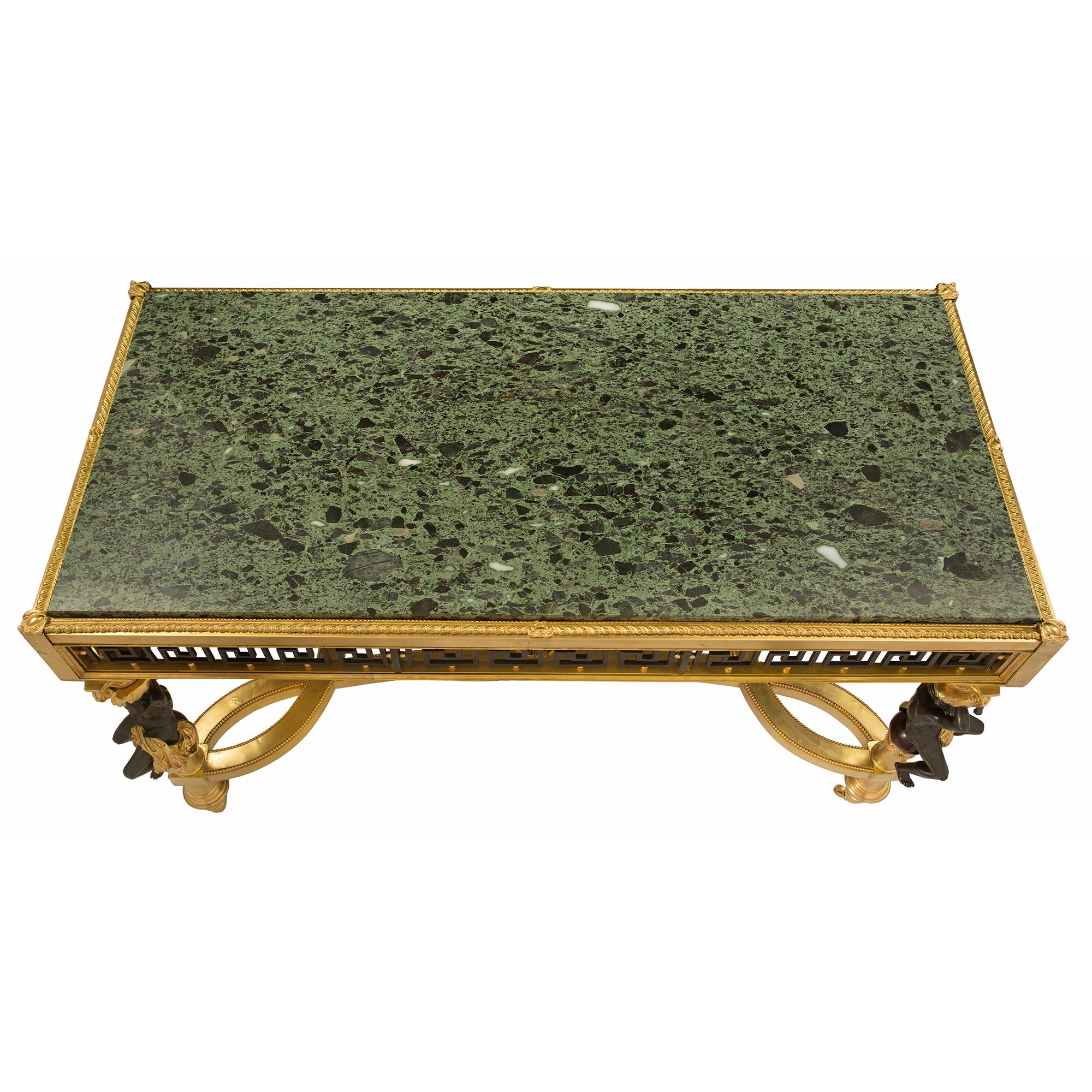 Sensationnelle table de centre en bronze doré, bronze patiné et marbre Vert Antique de style Louis XVI du 19ème siècle. La table est surélevée par ses roulettes d'origine sous d'élégants pieds cannelés en spirale. Chaque pied présente