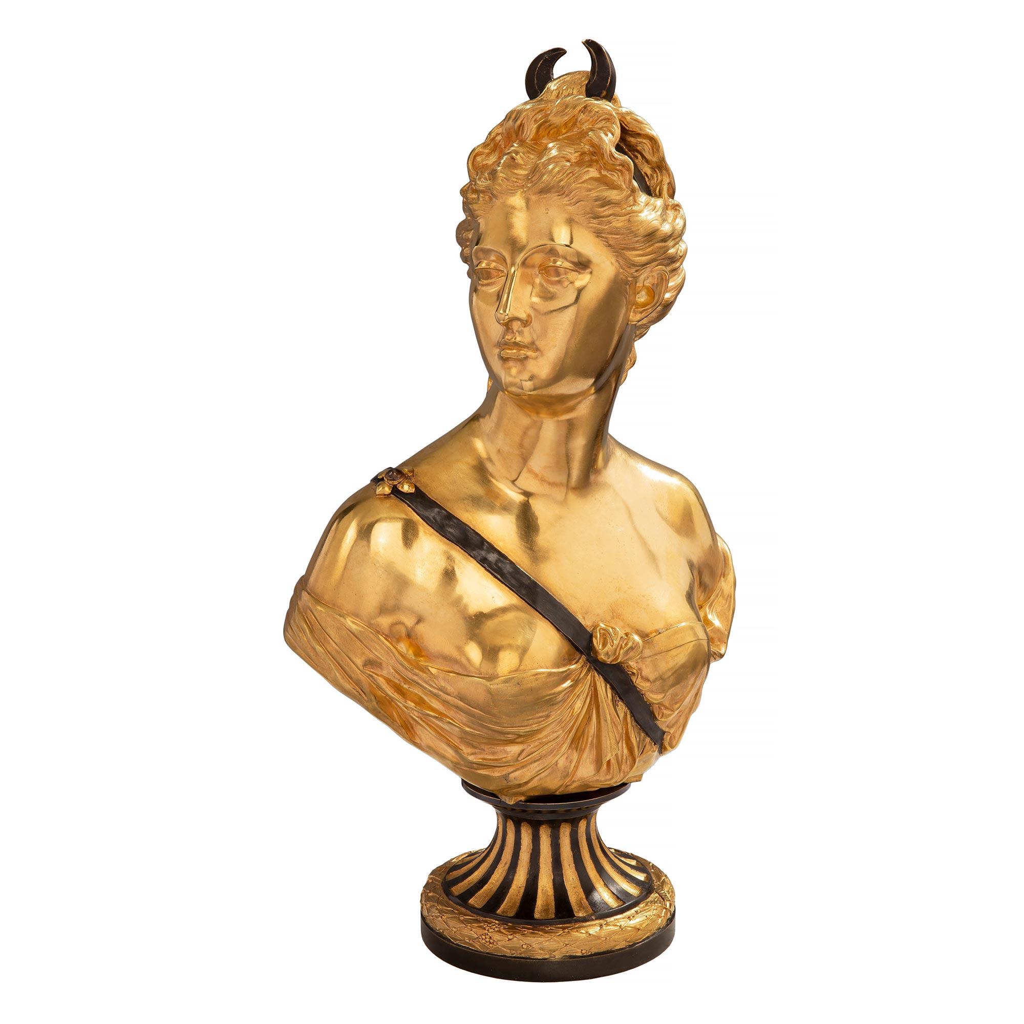 A striking French 19th century Louis XVI st. ormolu and patinated bronze bust of Diana the Huntress, signed Houdon and Susse Frères. The bust is raised by a striking circular base with a richly chased wrap around berried laurel band and a patinated