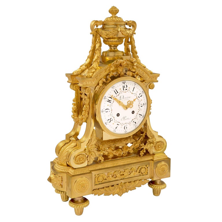 A stunning French 19th century Louis XVI st. ormolu clock signed by Denière. The clock is raised by elegant topie shaped feet below beautiful block rosettes. At the center is a richly chased scrolled foliate ormolu mount in a striking satin and