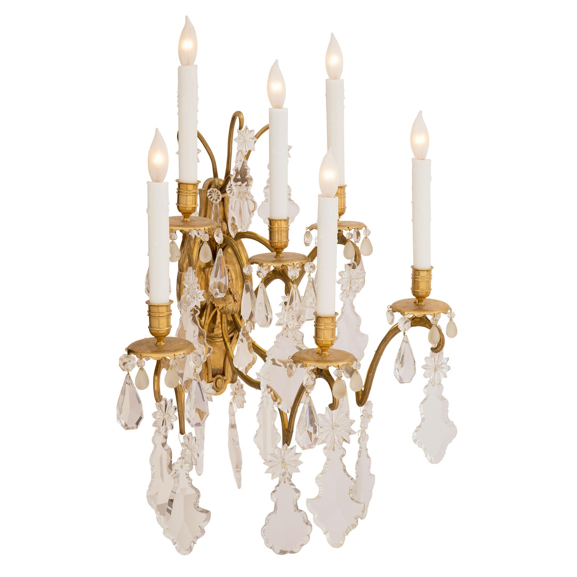 A most elegant pair of French 19th century Louis XVI st. ormolu, Baccarat crystal and frosted crystal six arm sconces. Each sconce is centered by a lovely mottled elongated back plate with a richly chased acanthus leaf from where the six uniquely