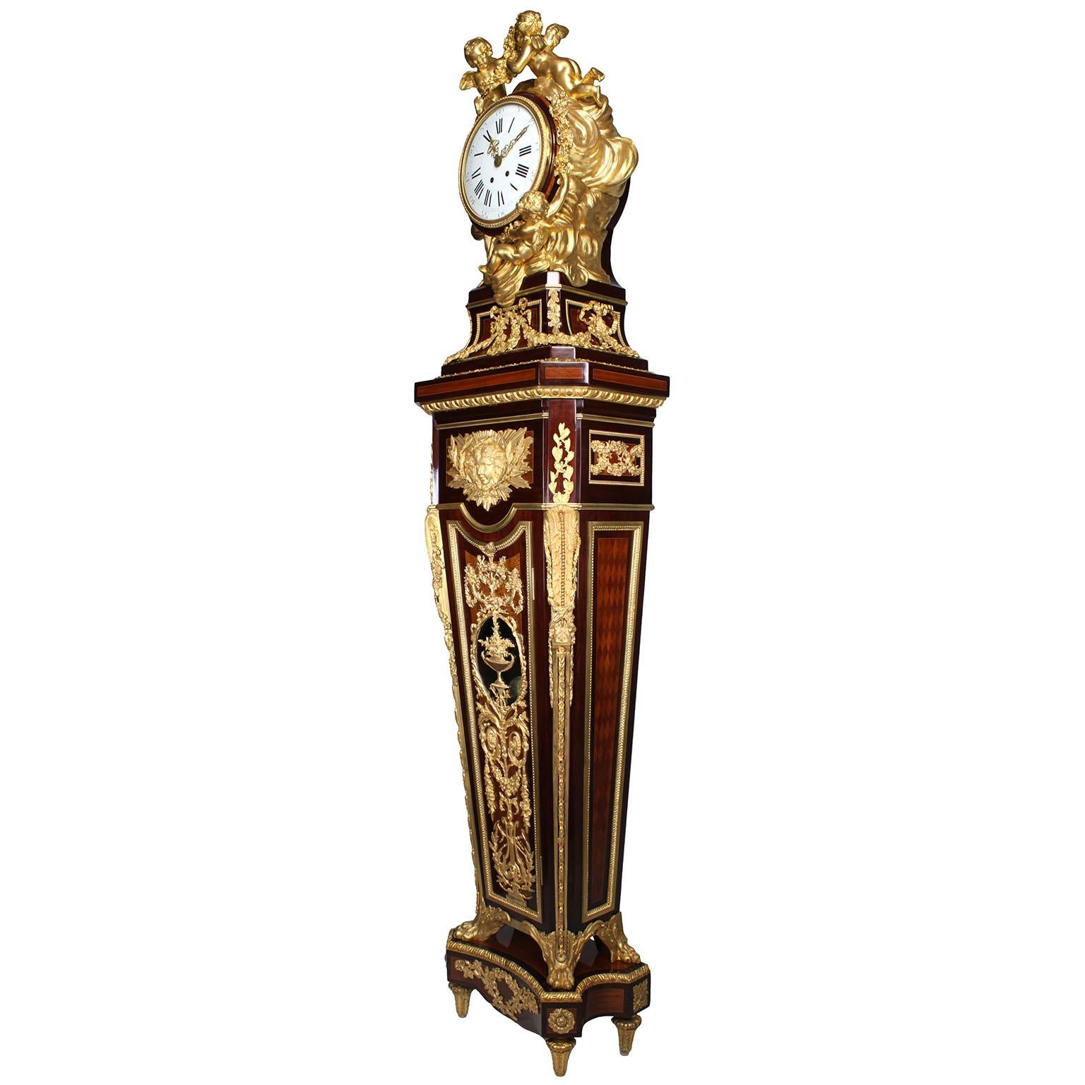 Très belle horloge française du XIXe siècle de style Louis XVI, montée sur un piédestal en amarante, tulipier, sycomore et parquet, et ornée de bronze doré. Pendule, d'après le modèle attribué à Jean-Henri HENRY, surmontée d'un boîtier en forme de