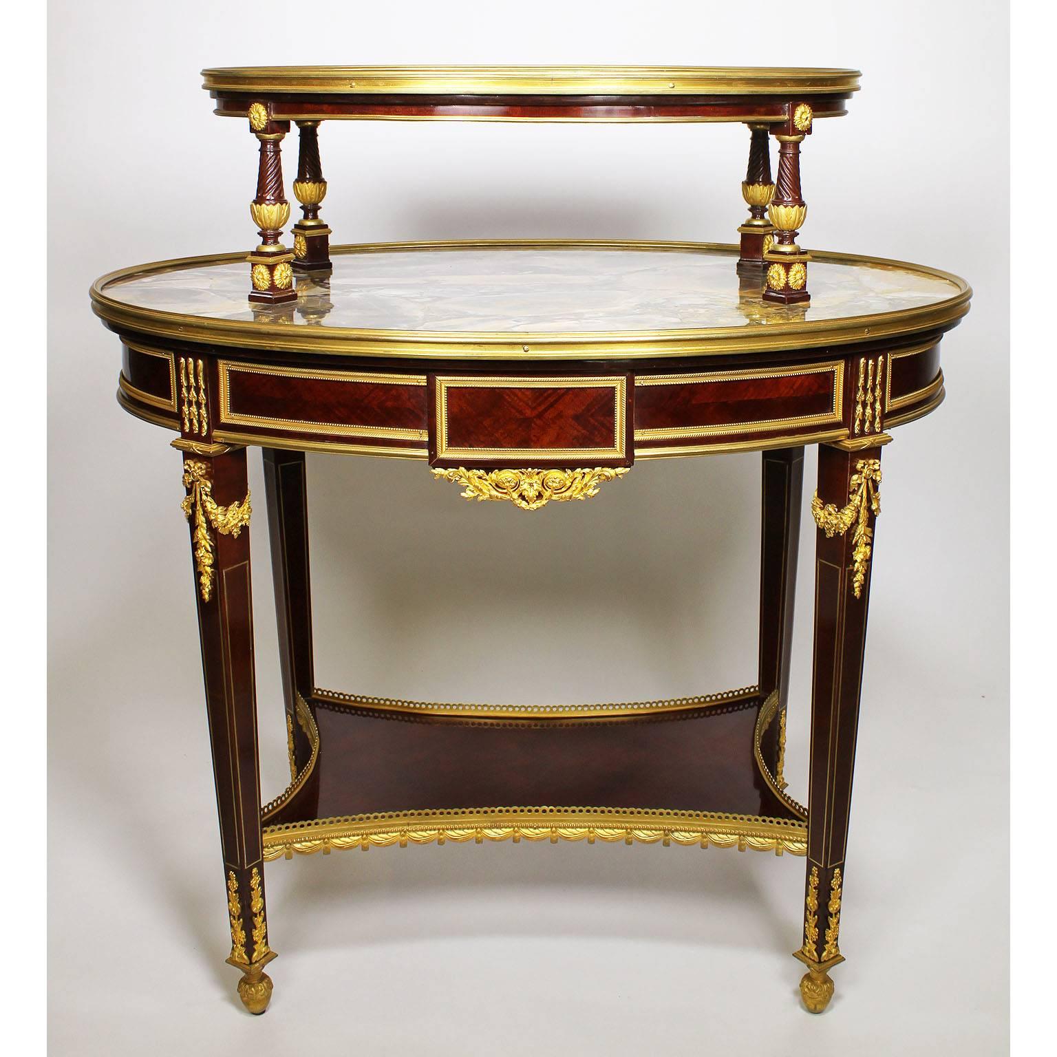 A very fine French, 19th century Louis XVI style ormolu-mounted mahogany two-tier tea-table etagere attributed to François Linke (1855-1946). The oval Basque Jaspe marble top with a gilt-bronze trimmed frame supported by four scrolled mahogany