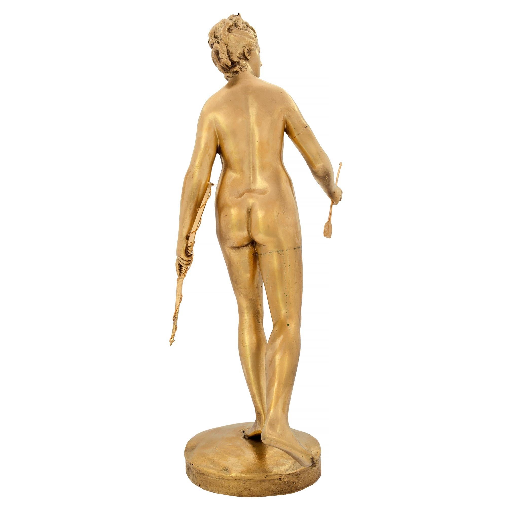 An elegant French 19th century Louis XVI st. ormolu statue of Diana the Huntress signed HOUDON. The famous statue is raised by a circular base with a ground like design where the signature is displayed. The richly chased Diana stands on her left leg