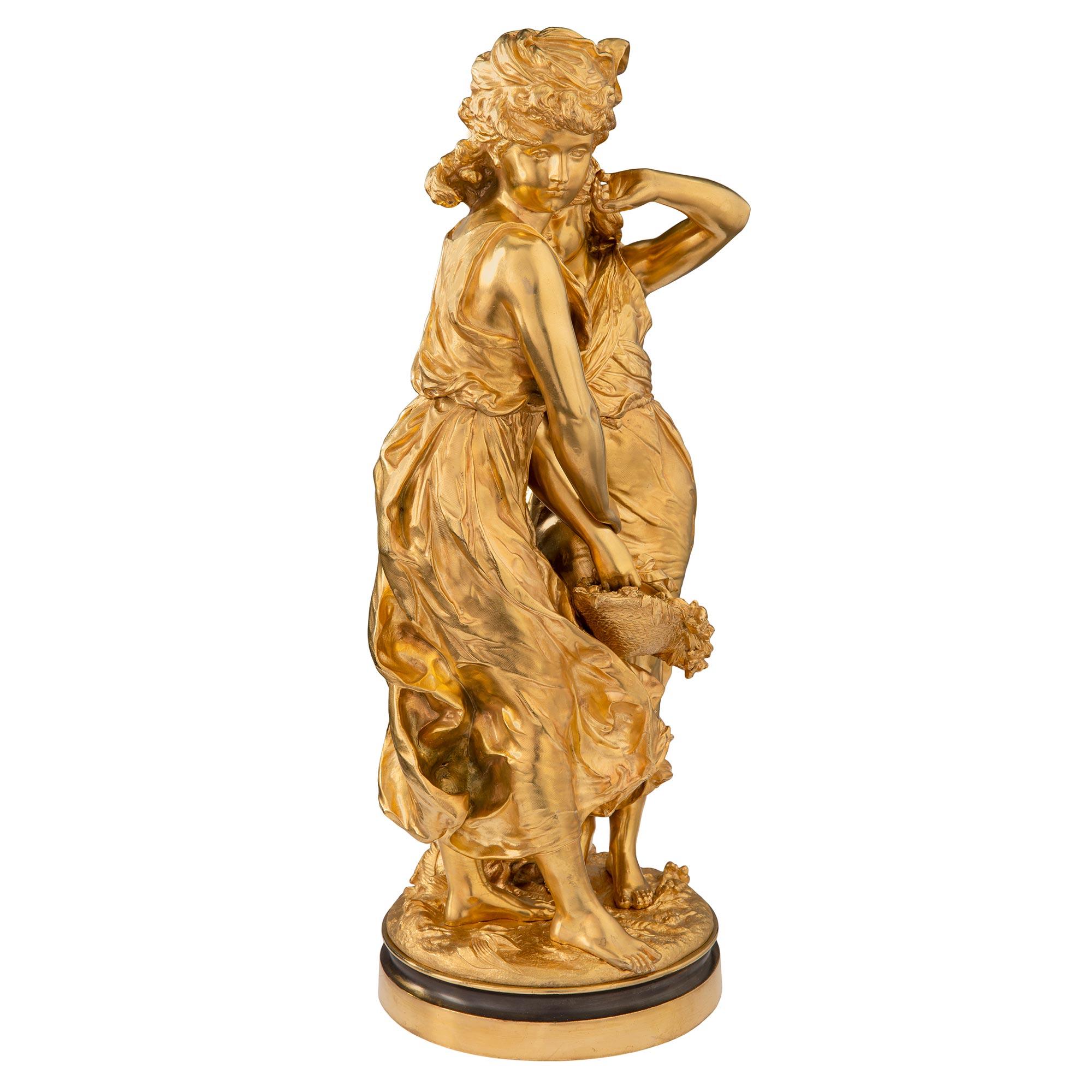 Preciosa estatua francesa de ormolina del siglo XIX, estilo Luis XVI, de gran calidad, de dos bellas doncellas, firmada Moreau. La estatua se eleva sobre una fina base circular moteada con un destacado diseño en el suelo. Encima hay dos encantadoras