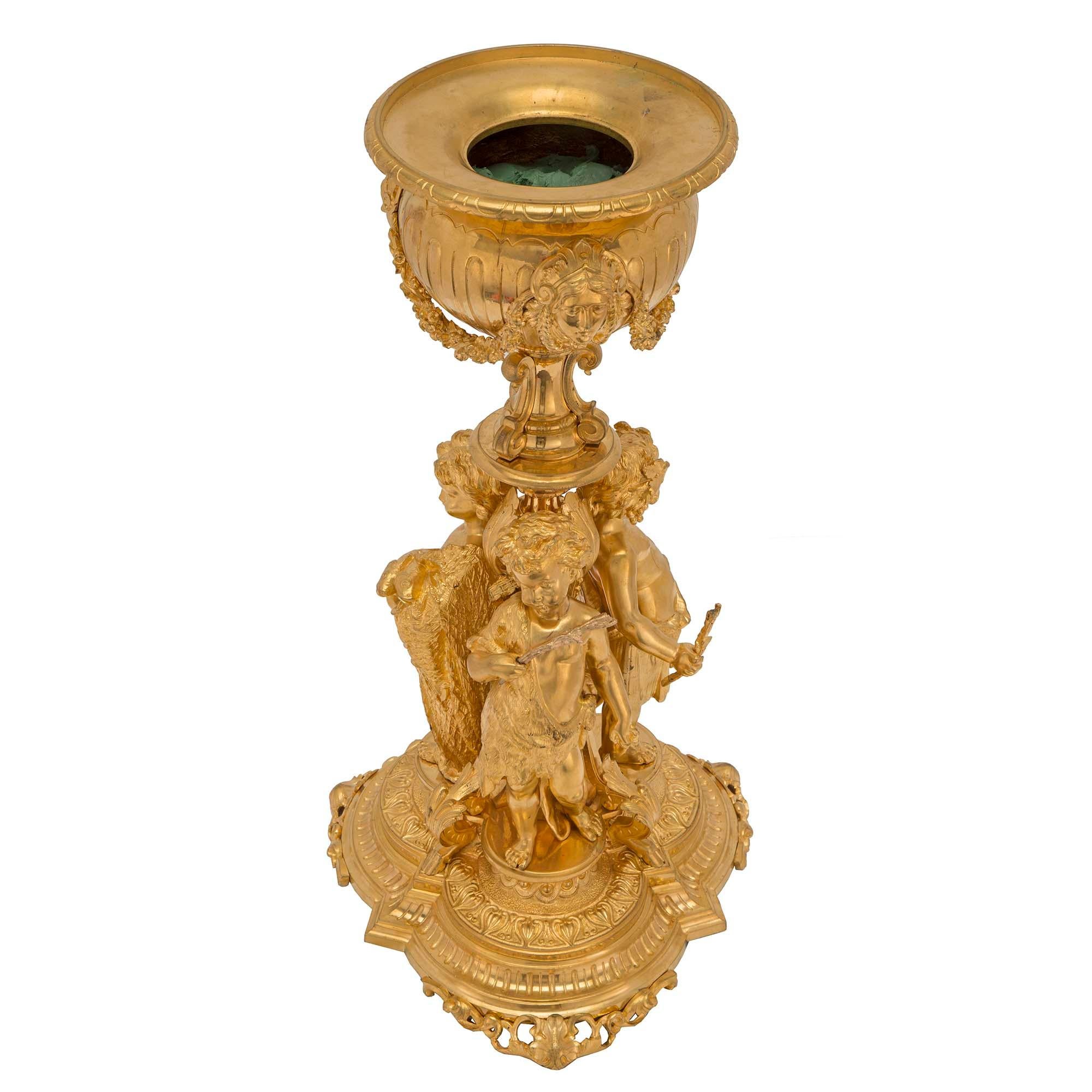 Eine exquisite französische Ormolu-Urne aus dem 19. Jahrhundert im Stil Louis XVI. Die Urne steht auf einem fein ziselierten, gewellten Sockel mit durchbrochenen Füßen. An der Säule sind drei verspielte Putten zu sehen, von denen eine als Jäger mit
