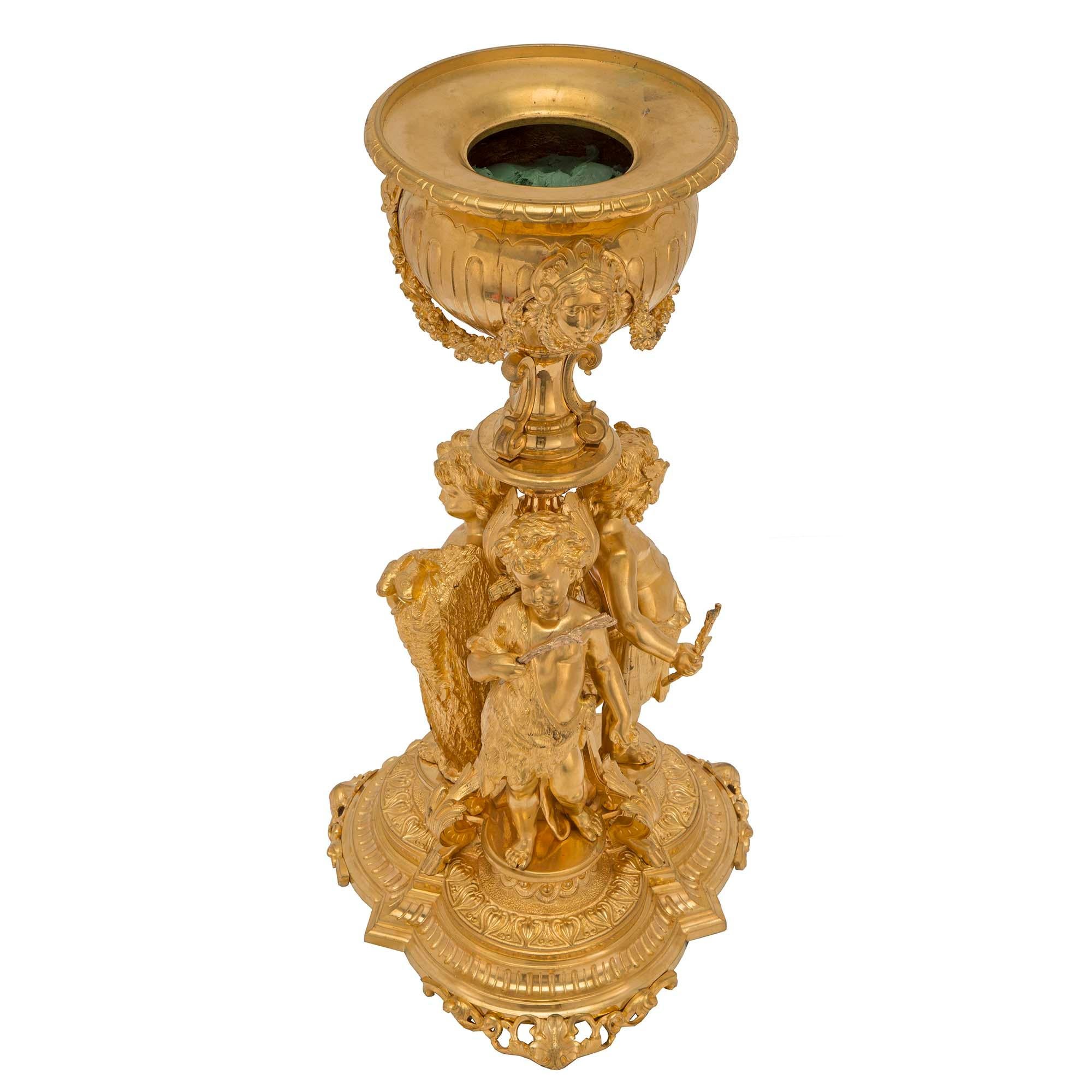 Una squisita urna francese del XIX secolo in stile Luigi XVI in ormù. L'urna è sollevata su una base smerlata finemente cesellata con piedi forati. Sulla colonna ci sono tre putti giocosi, uno vestito da cacciatore con una faretra di frecce sulla