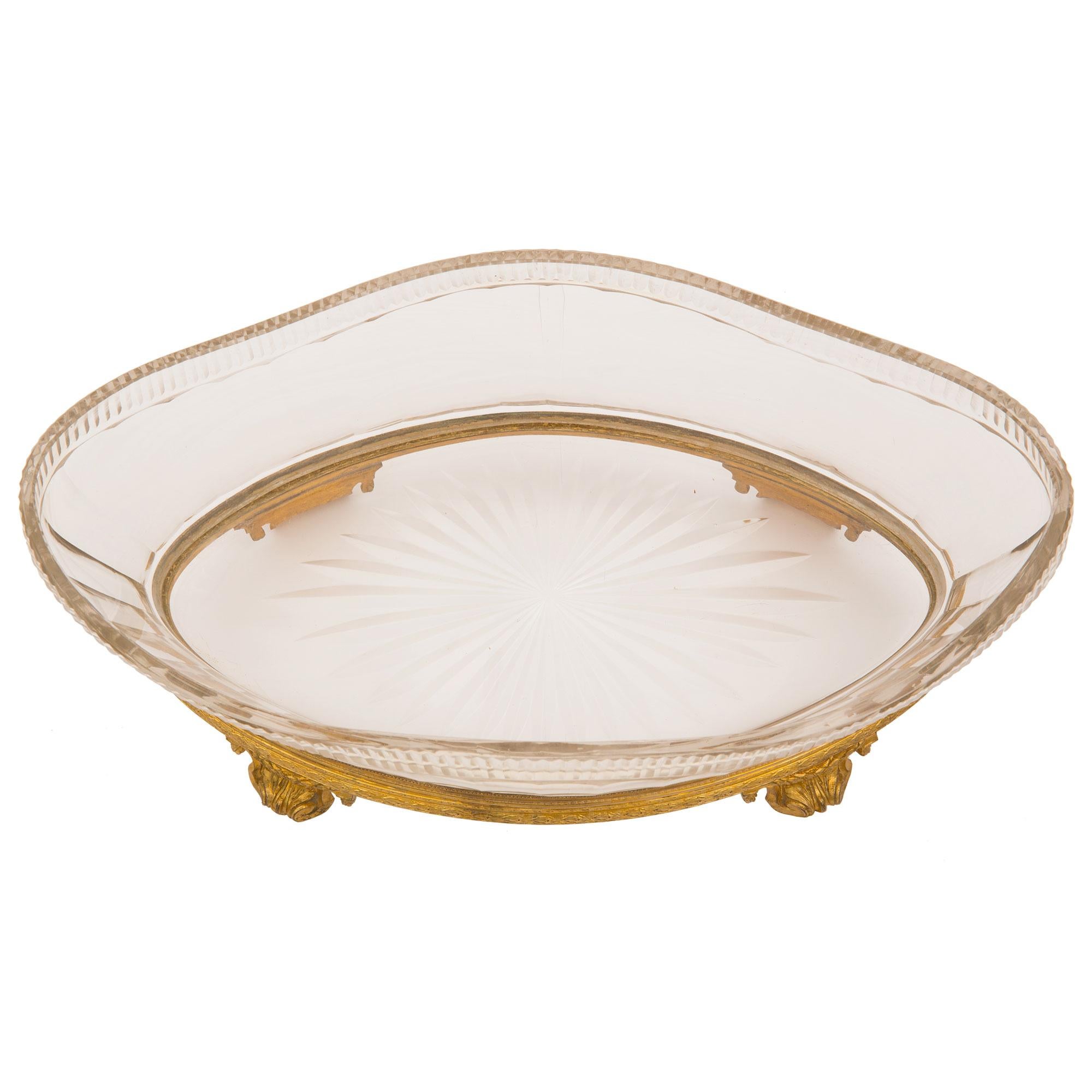 An exquisite French 19th century Louis XVI st. Baccarat crystal and ormolu oval shaped centerpiece bowl. The centerpiece is raised by elegant scrolled foliate supports with delicate swaging laurel garlands. A fine berried laurel garland wraps around