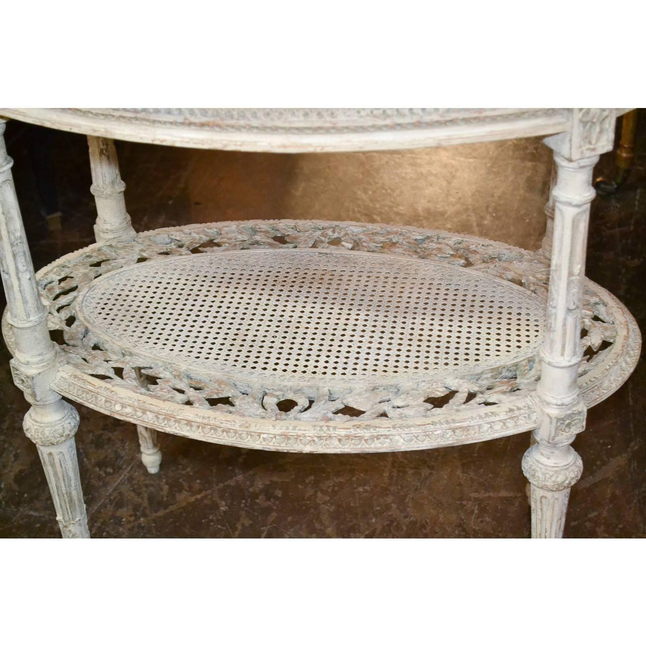 Pretty oval occasional table handcrafted and hand-painted in soft off-white.
Complimentary colored bevelled marble top. Cane work on shelf is in very good condition.
Made in France in the Louis XVI style, circa 1880.