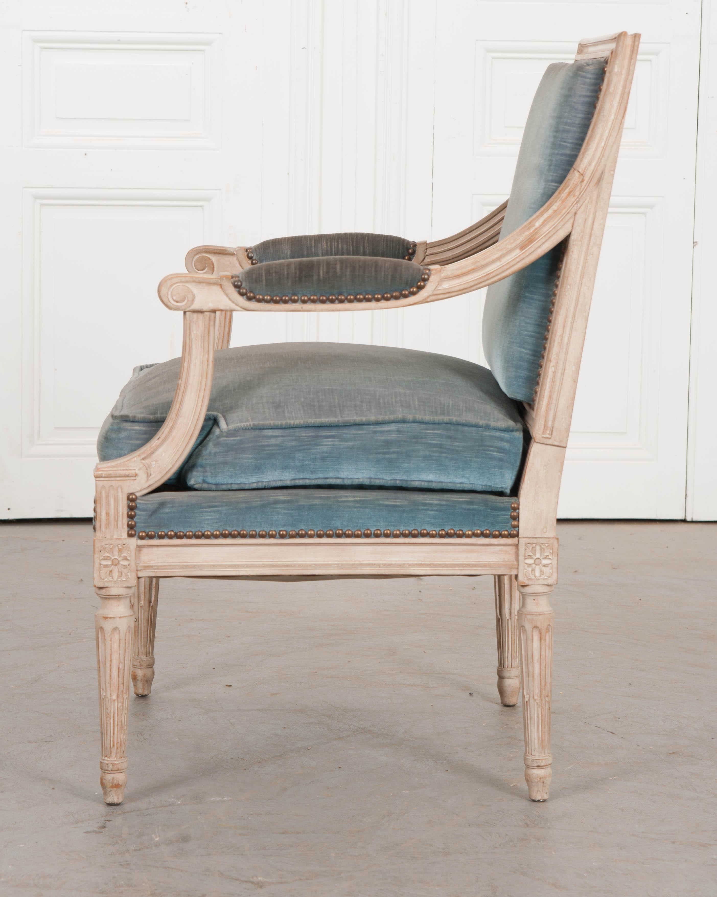 This elegant Louis XVI-style painted fauteuil, circa 1880, is from France and features a squared crest over padded open arms and having rosette and fluted tapering legs. Upholstered in a beautiful pale-cerulean velvet.