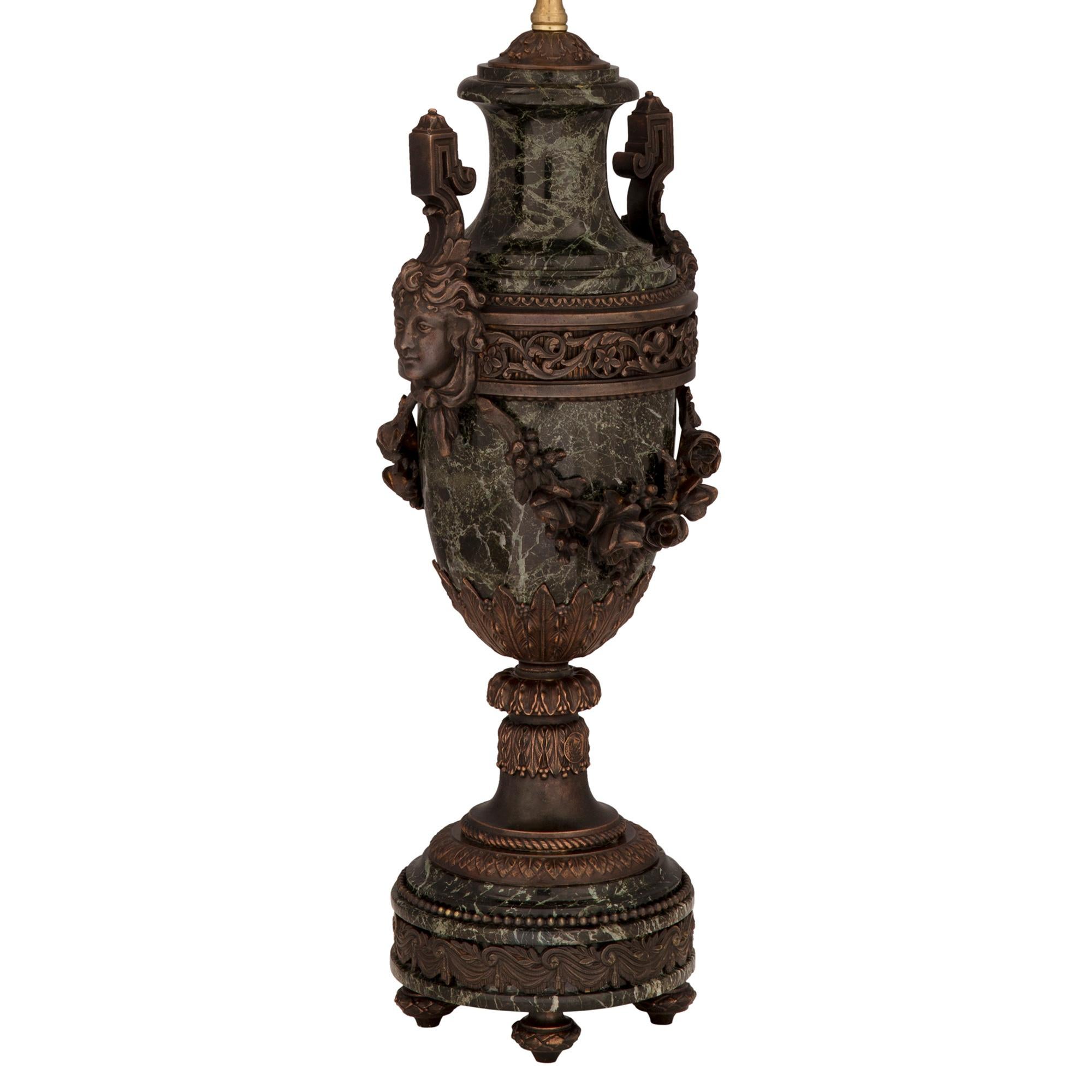 An elegant French 19th century Louis XVI st. patinated bronze, ormolu and Vert de Patricia marble lamp. The lamp is raised by fine topie shaped feet with a lovely berried laurel band. The Vert de Patricia circular base displays a beautiful fitted