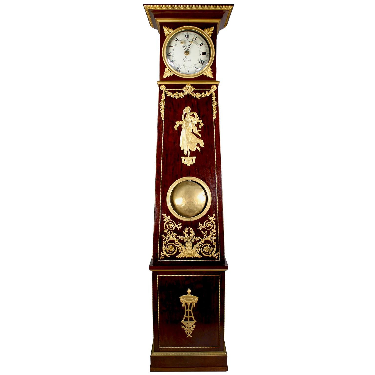 A Very Fine French 19th Century Louis XVI Style Plum-Mahogany and Ormolu Mounted Tall-Case Regulator attributed to Revollon. The Roman numeral dial signed: Revollon - M. Lion, with hands ending in the shape of a sunburst, the tall and slender case