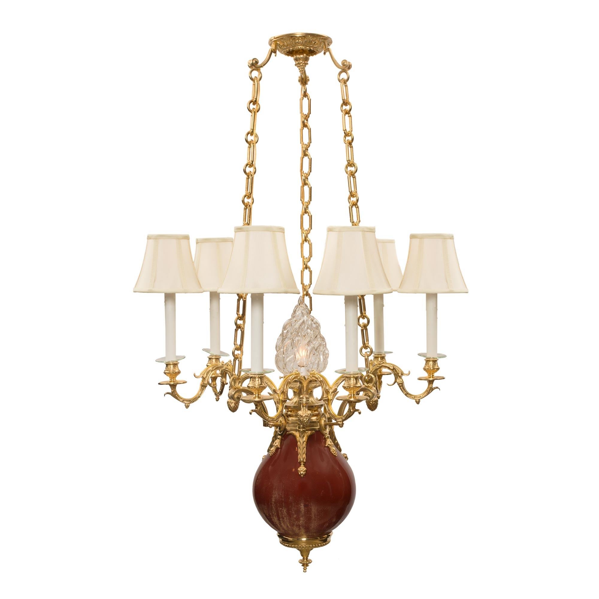 A unique and most decorative French 19th century Louis XVI st. oxblood porcelain and ormolu six arm, seven light chandelier. The chandelier is centered by a fine topie shaped ormolu bottom finial with an elegant beaded wrap around band and lovely