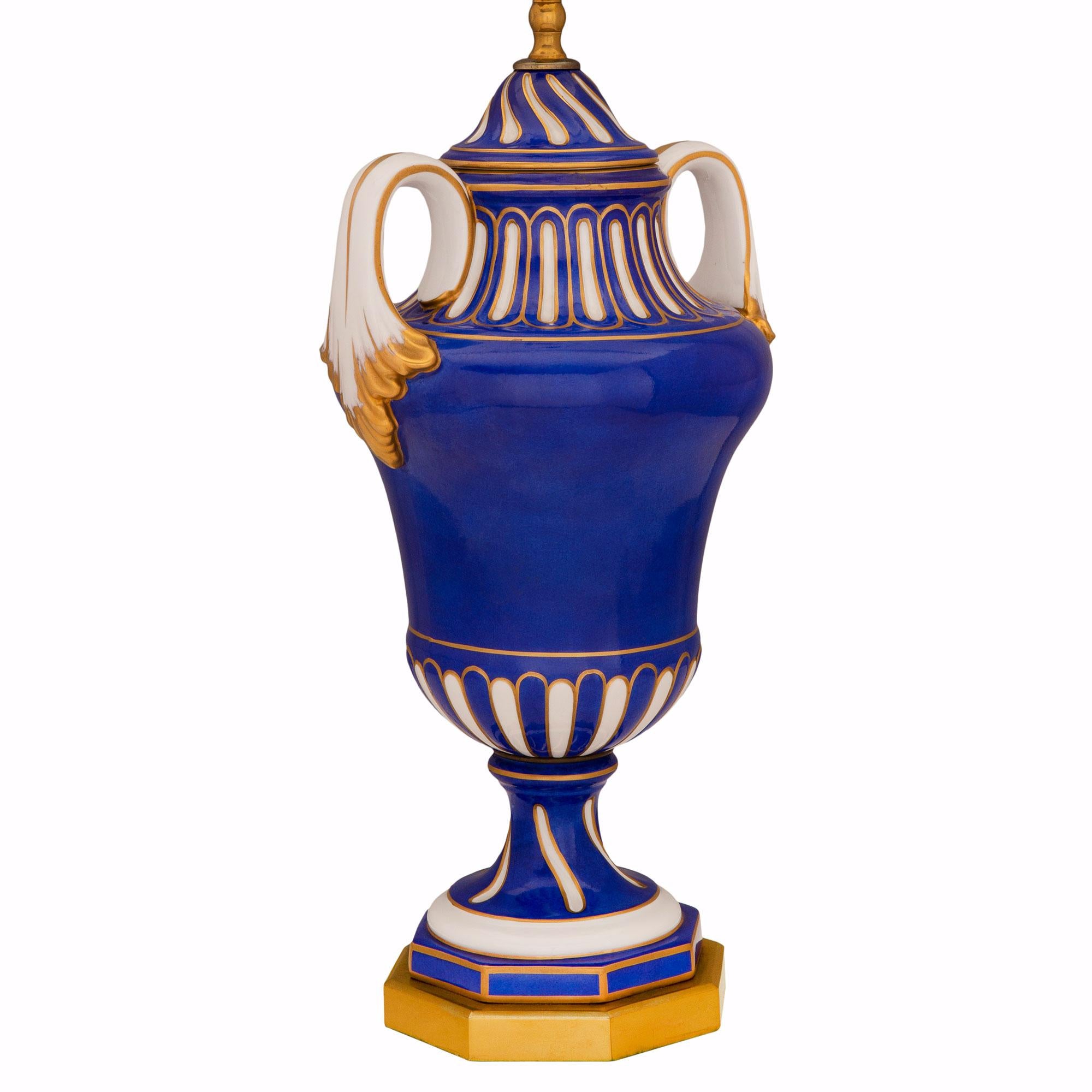 A most decorative French 19th century Louis XVI st. 'Porcelain de Paris' and ormolu urn mounted into a lamp. The lamp is raised by an elegant octagonal ormolu base below the lovely blue and white socle shaped pedestal with fine gilt fillets. The
