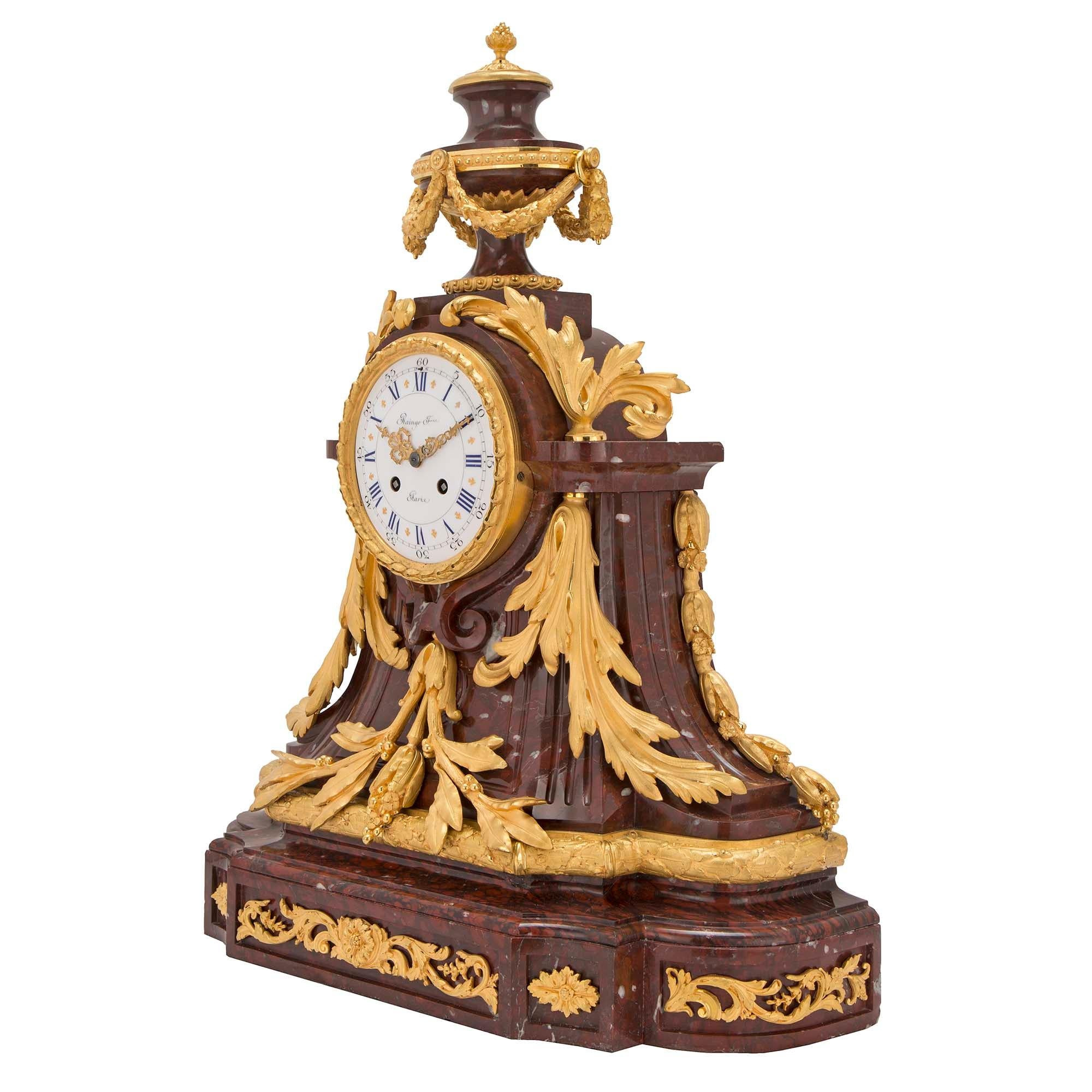 A magnificent French 19th century Louis XVI st. Rouge Griotte marble and ormolu clock by Raingo Frères, Paris. At the base are stunning ormolu mounts of rosettes and scrolled foliate, at the front and sides. The fluted marble body has a thick laurel